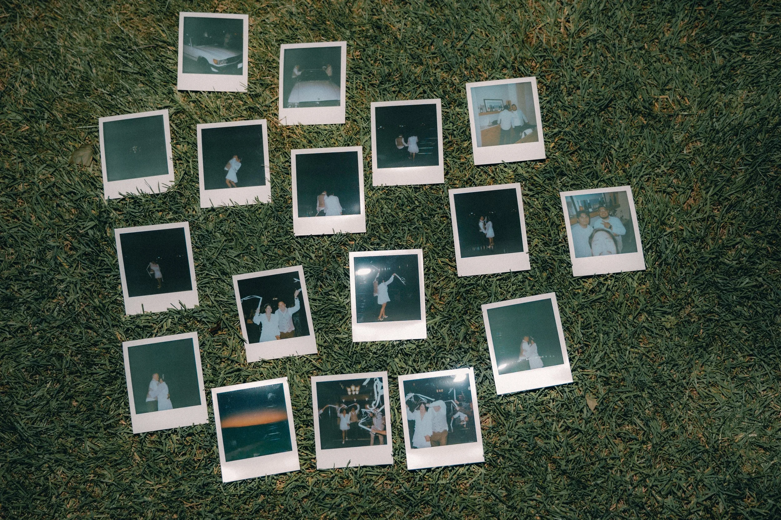 Polaroid photographs spread out on grass, depicting people at nighttime events and a few cars.