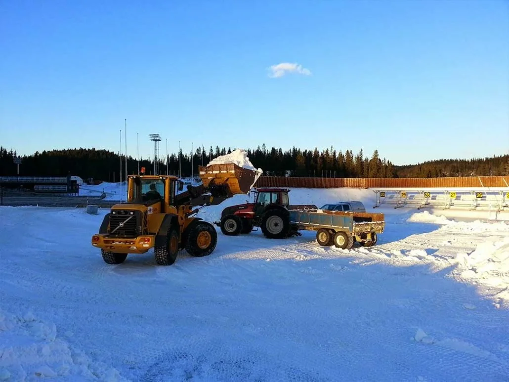 Snørydding med en stor gravemaskin og traktor på en vinterdag.
