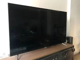 Large flat-screen TV on a wooden cabinet in a living room.