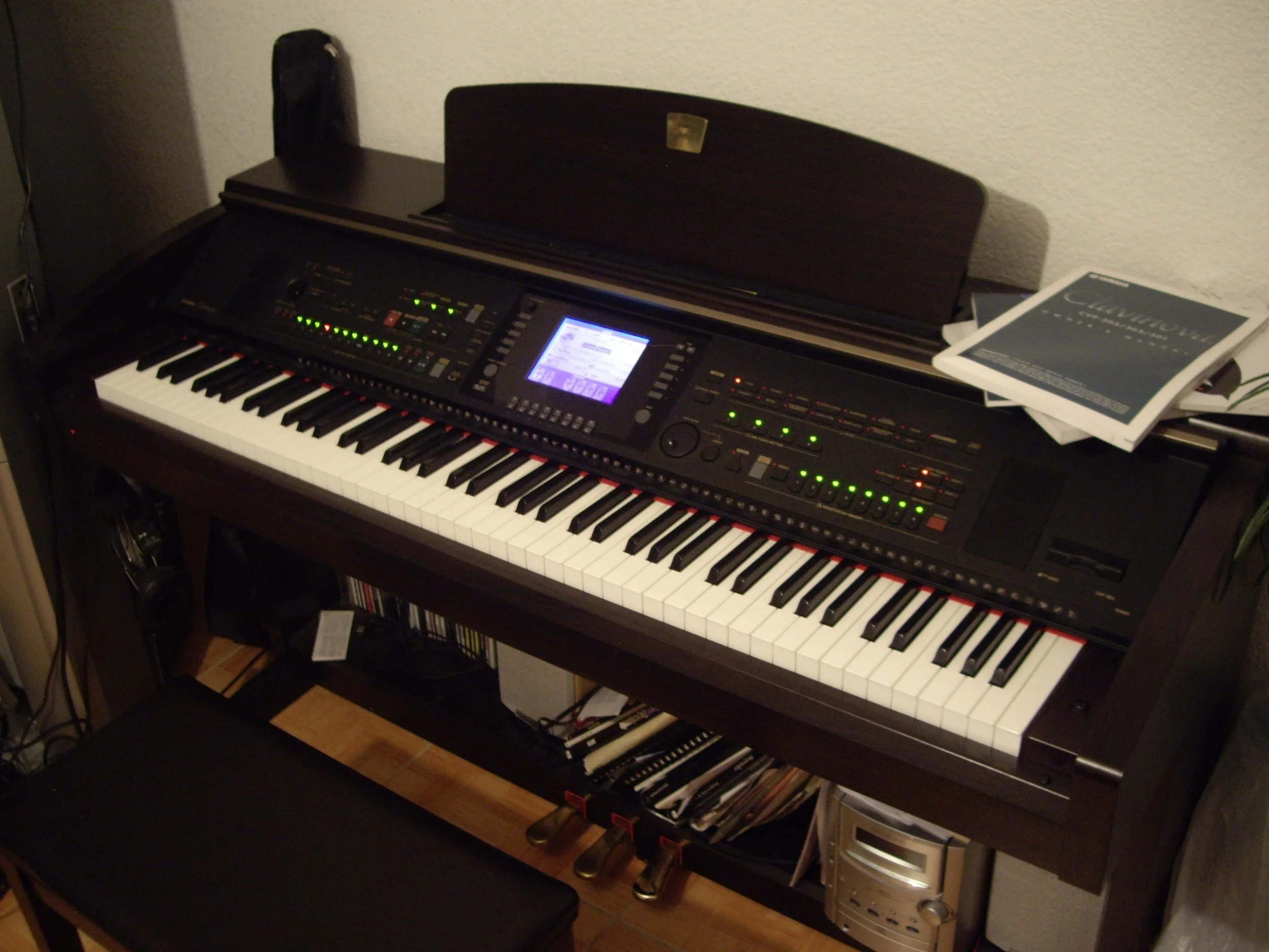 A digital keyboard placed on a wooden stand, with a sheet music book open on the top right side of the keyboard, and a piano bench below the keyboard.