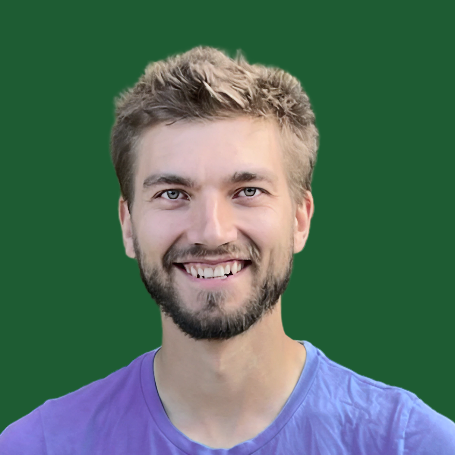 Portrait of a smiling young man with light brown hair, beard, and blue eyes, wearing a purple T-shirt, against a solid green background.