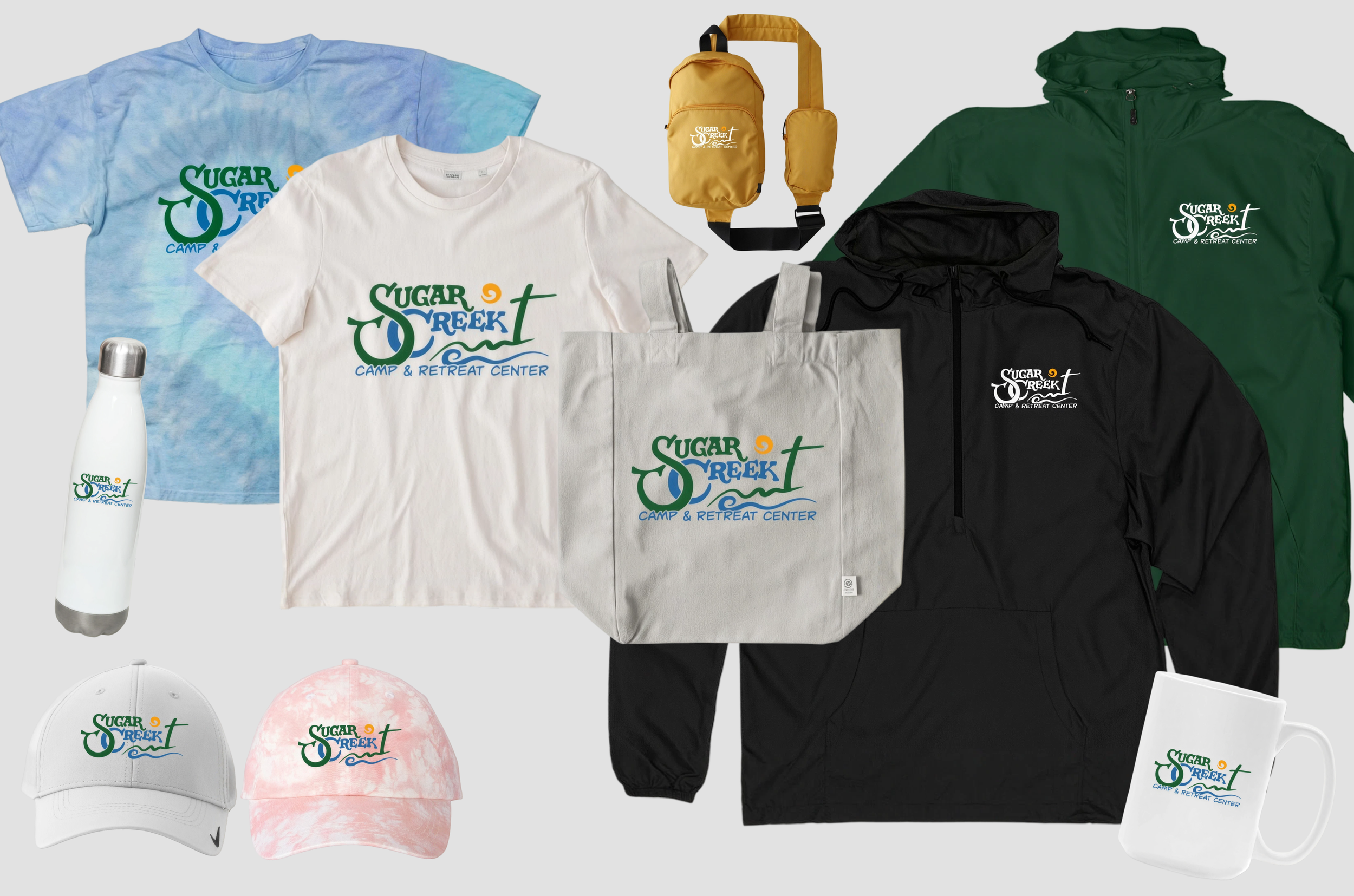 Collection of promotional merchandise including T-shirts, jackets, tote bags, water bottle, hats, umbrella, and mugs, all branded with the Sugar Creek Camp & Retreat Center logo.