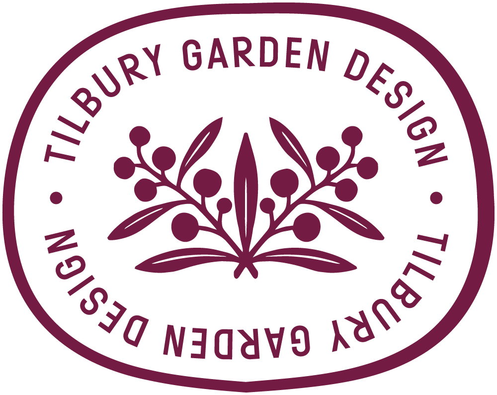 An irregular stamp logo with the text "Tilbury Garden Design" written around the border. Inside, there is an illustration of an acacia plant with multiple branches, leaves and flowers.