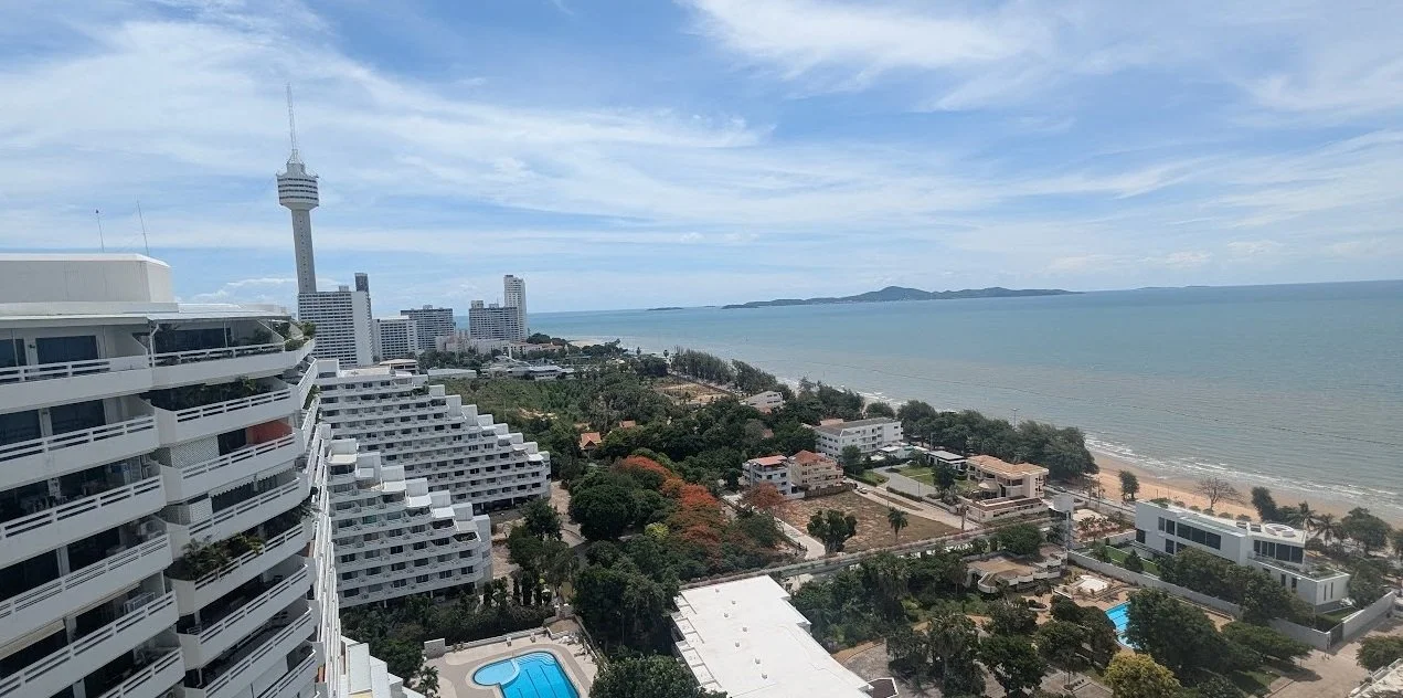 A cityscape with a tall observation tower and high-rise buildings near a beach with ocean views.