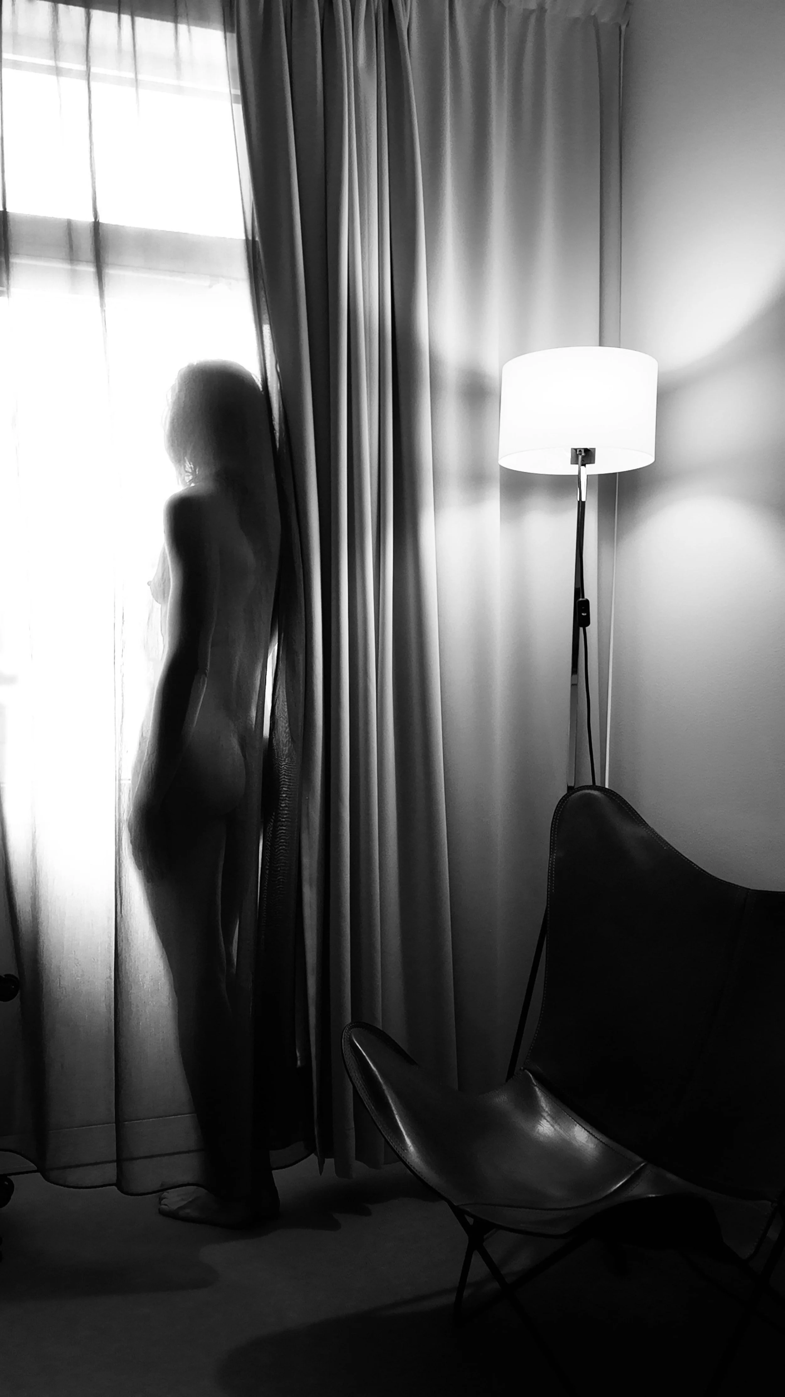 Amanita Grace bokningsförfrågan, stämningsfull och sensuell svartvit bild vid ett fönster.