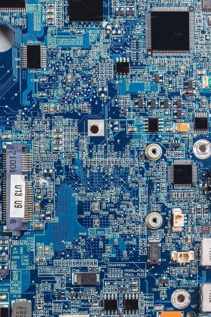 Close-up of a blue computer motherboard with various electronic components, chips, resistors, and connectors.