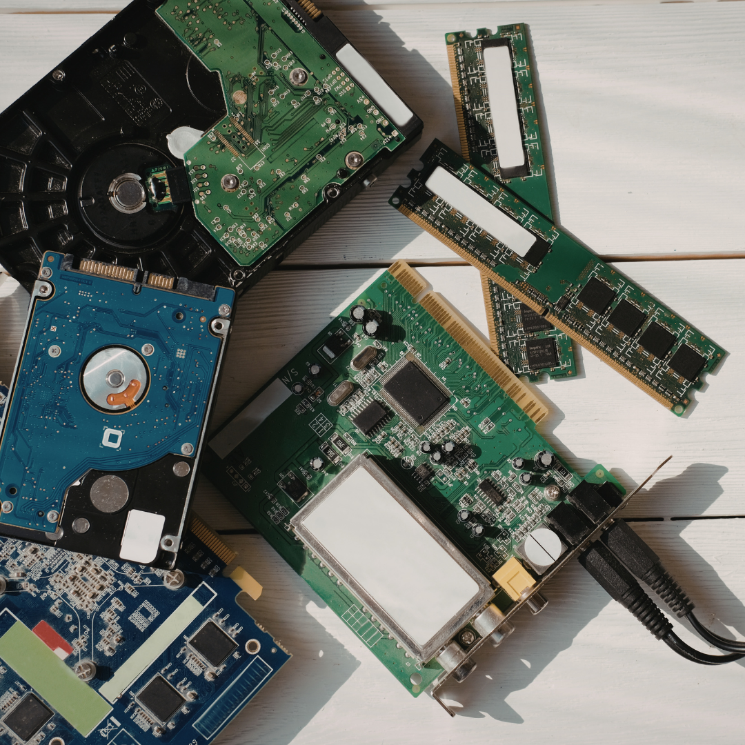 Various computer hardware components, including hard drives and RAM modules, arranged on a white wooden surface.