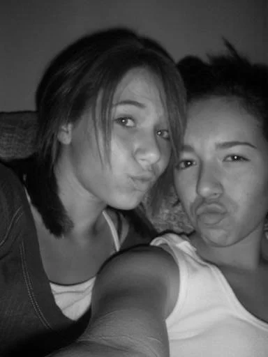Two young women making duck faces, taking a selfie together in black and white.