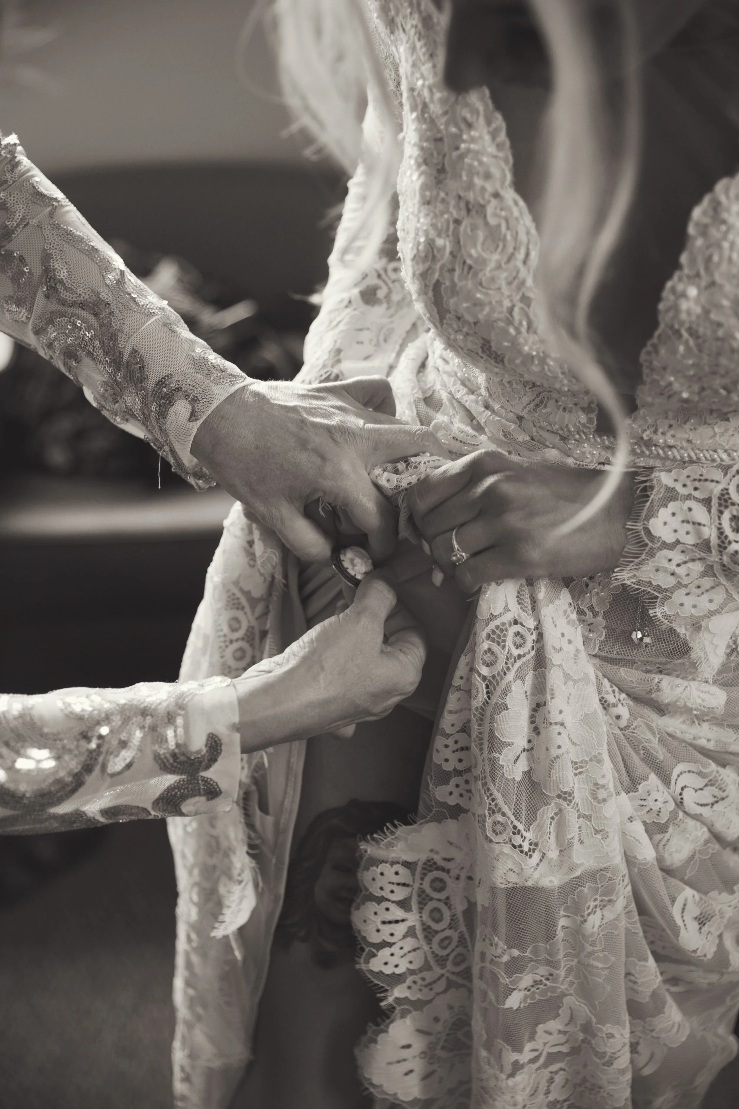Close-up of someone arranging a lace wedding dress, with intricate lace detailing and embroidery.