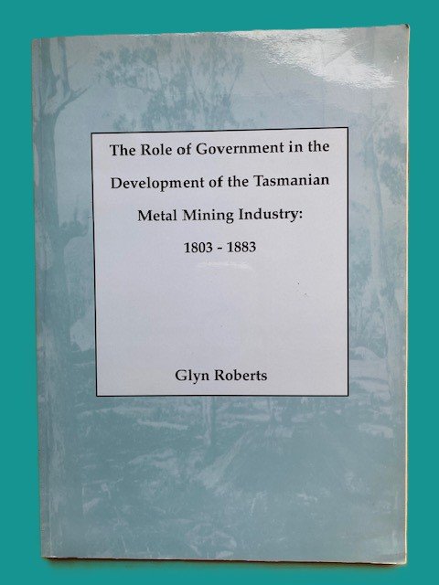 A book titled "The Role of Government in the Development of the Tasmanian Metal Mining Industry: 1803-1883" by Glyn Roberts, placed on a surface against a teal background.