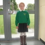 A young girl standing in front of a glass door.