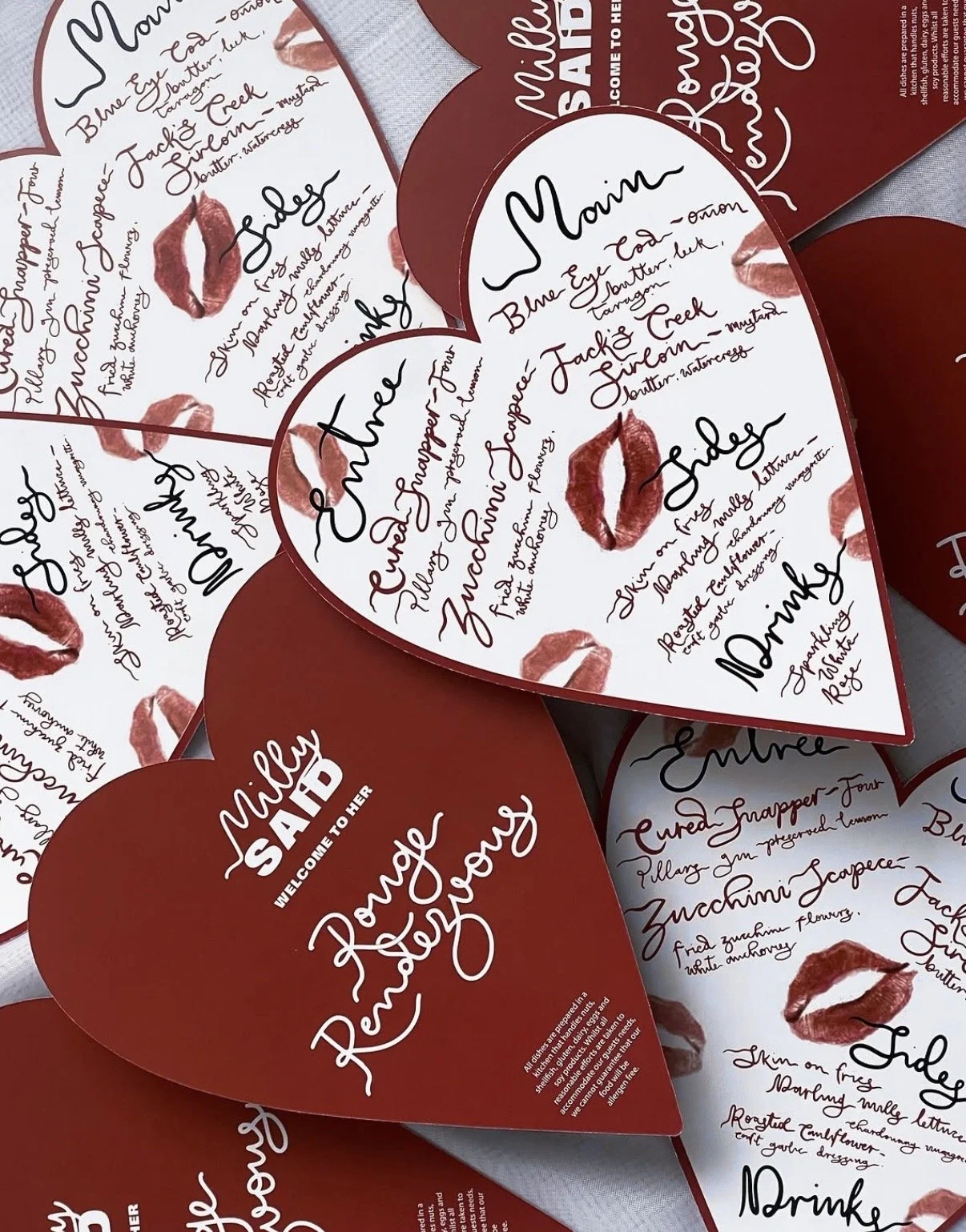 Multiple red heart-shaped cards with love-themed messages and lipstick kiss marks, including the words 'Main', 'Side', 'Enter', 'Drink', and 'Refill', welcoming someone to her. The cards have handwritten-style text and decorative cursive writing.