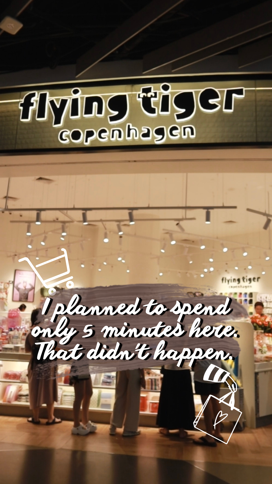 People shopping inside a Flying Tiger Copenhagen store with a sign above the entrance and shopping carts emoji in the image.