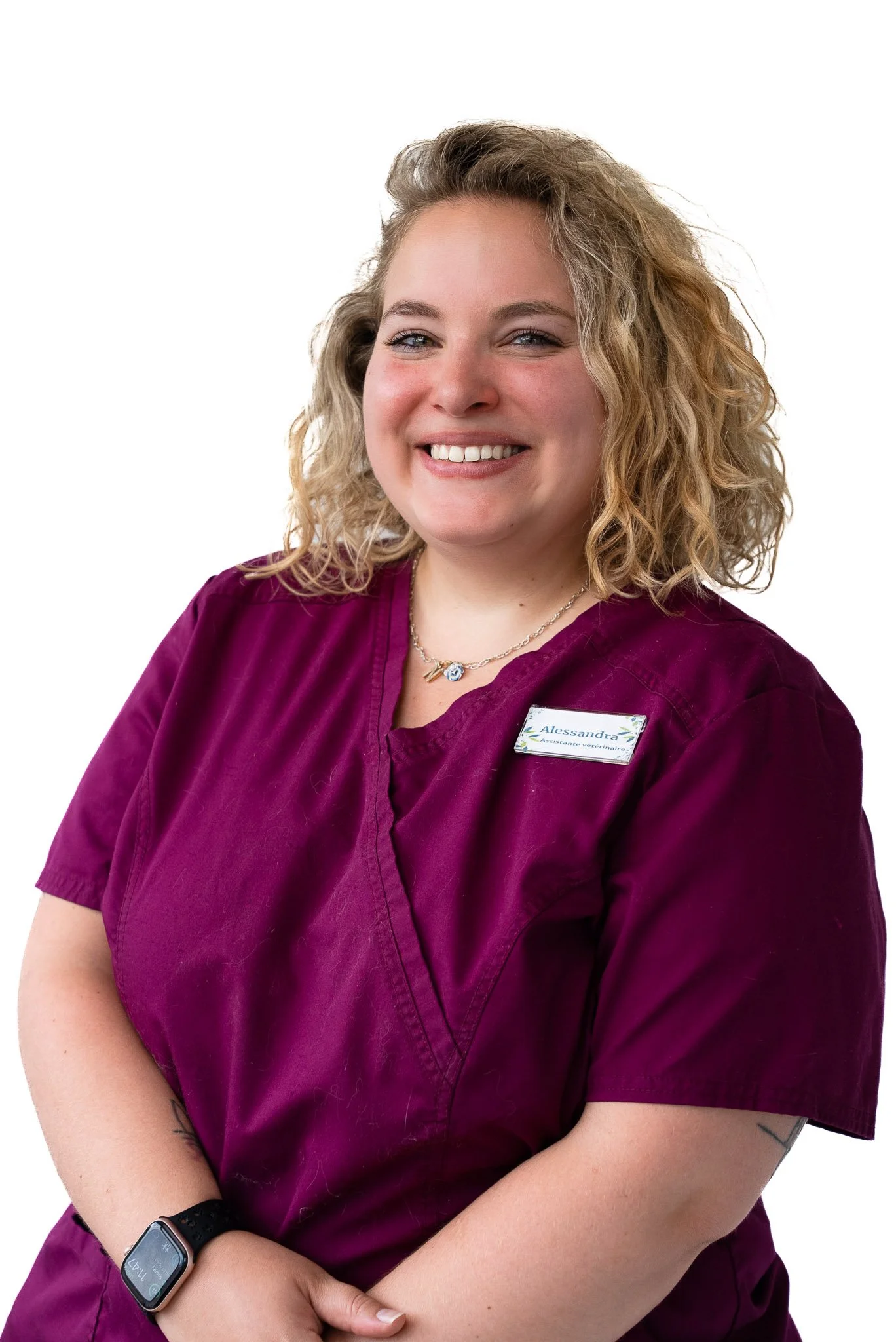 Staff member in purple medical scrubs, smiling, white background.