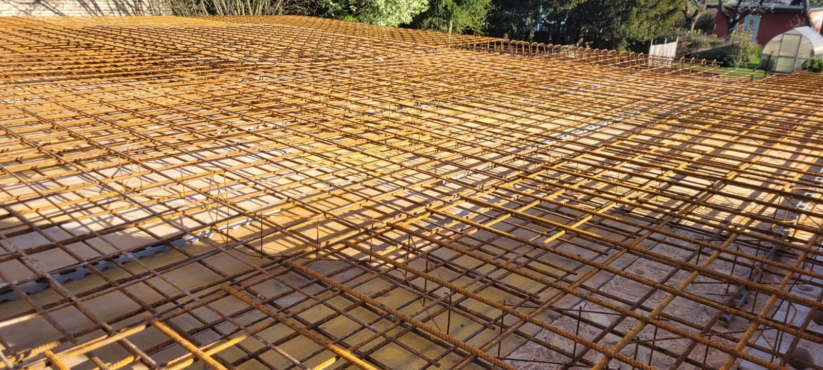 Baugerüst aus Metallstahl auf einem Baugrundstück, Umgebung mit Bäumen und Garten