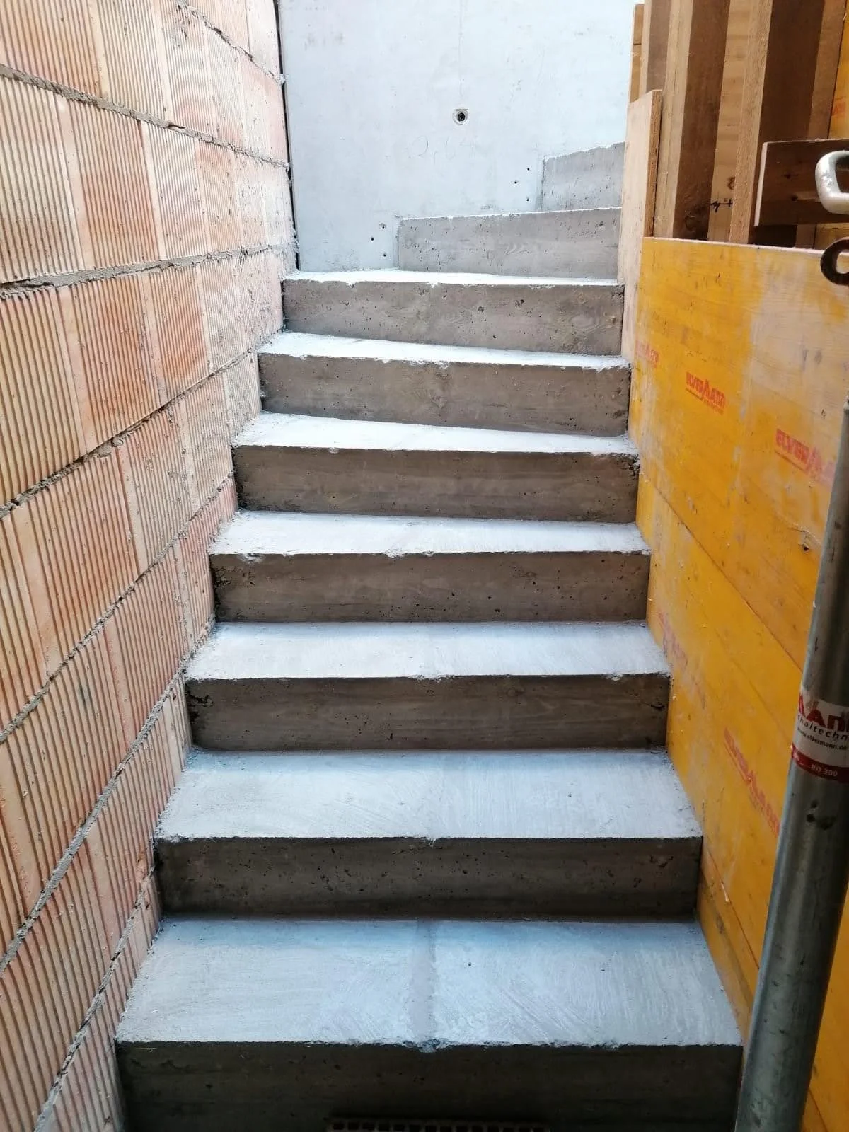 Betontreppe in einem Baukran mit Ziegel- und Gipswänden im Hintergrund.