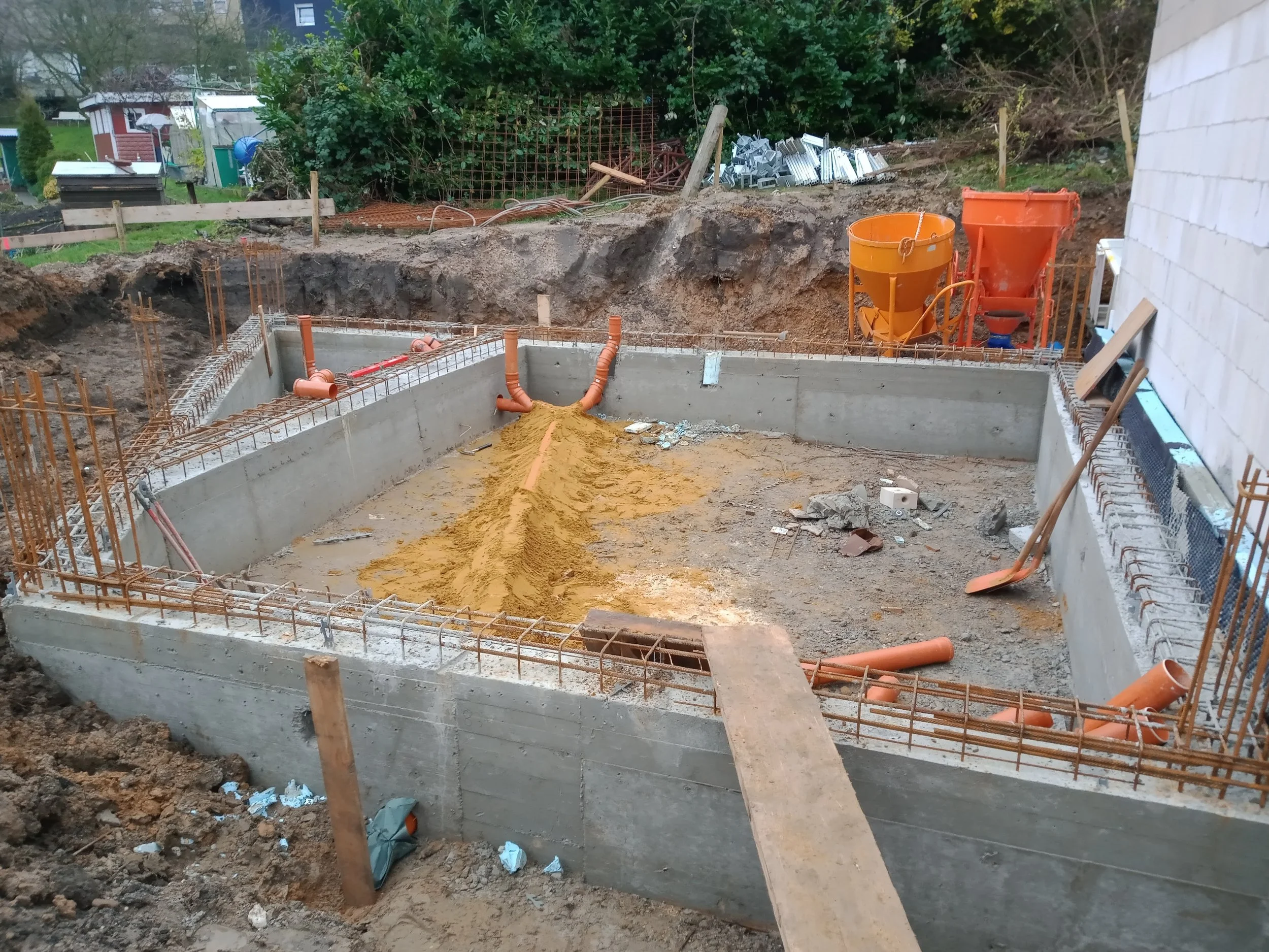 Baustelle mit Fundament, orange Rohre und Baugerüst