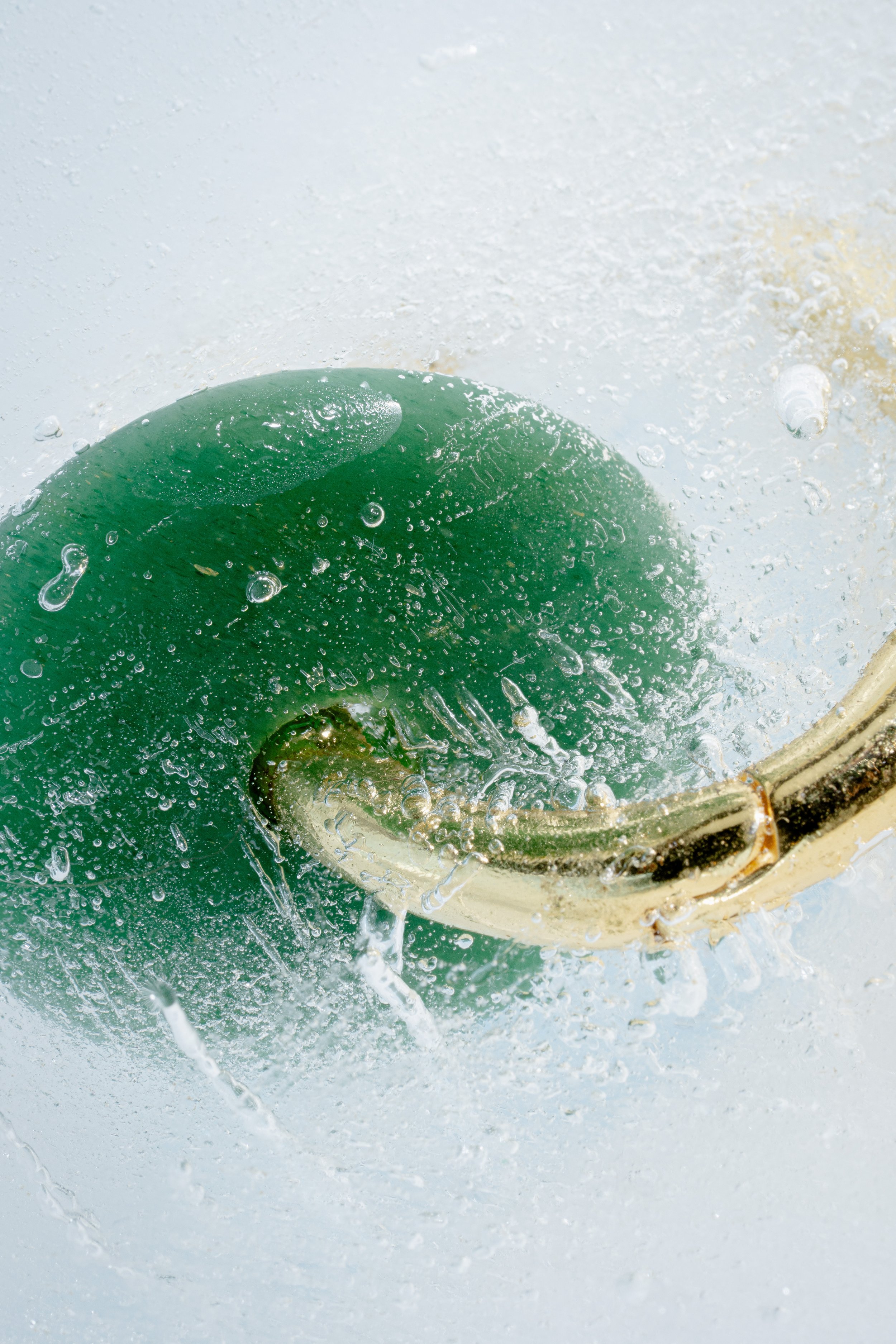 Close-up of a green fishing bobber submerged in water, with splashes and bubbles around it.