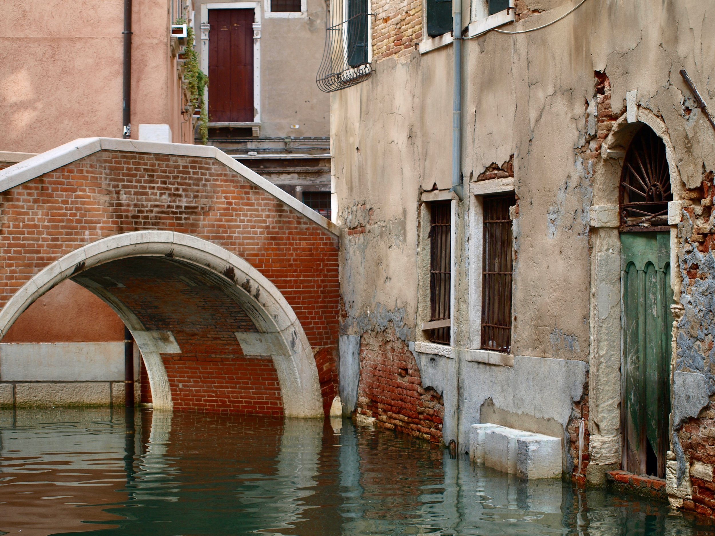 Un vieux bâtiment en pierre et en brique avec des fenêtres à barreaux et un pont en arc sur un canal d'eau.