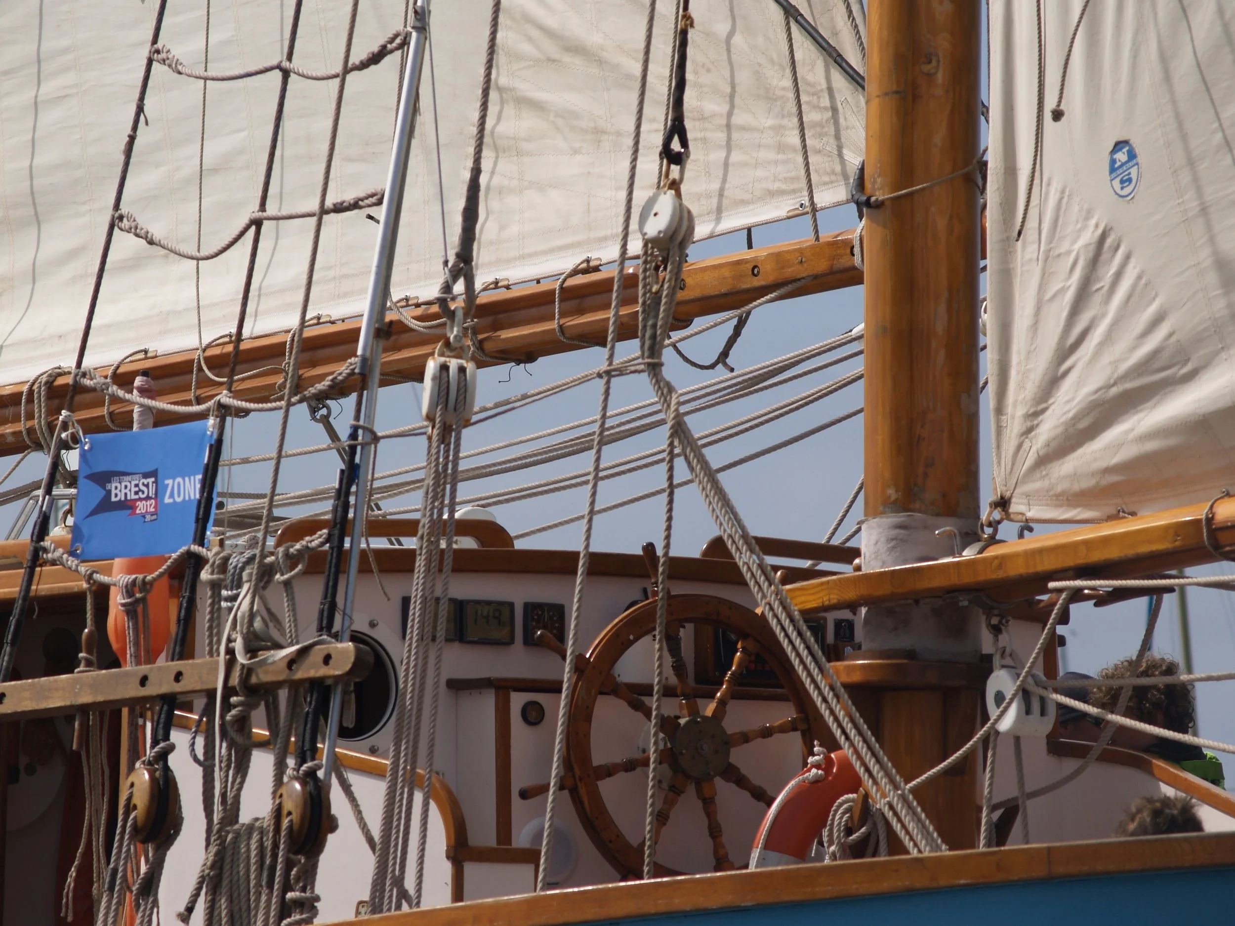 Navire en bois avec des cordages, voiles et un tableau de bord visible, probablement un voilier