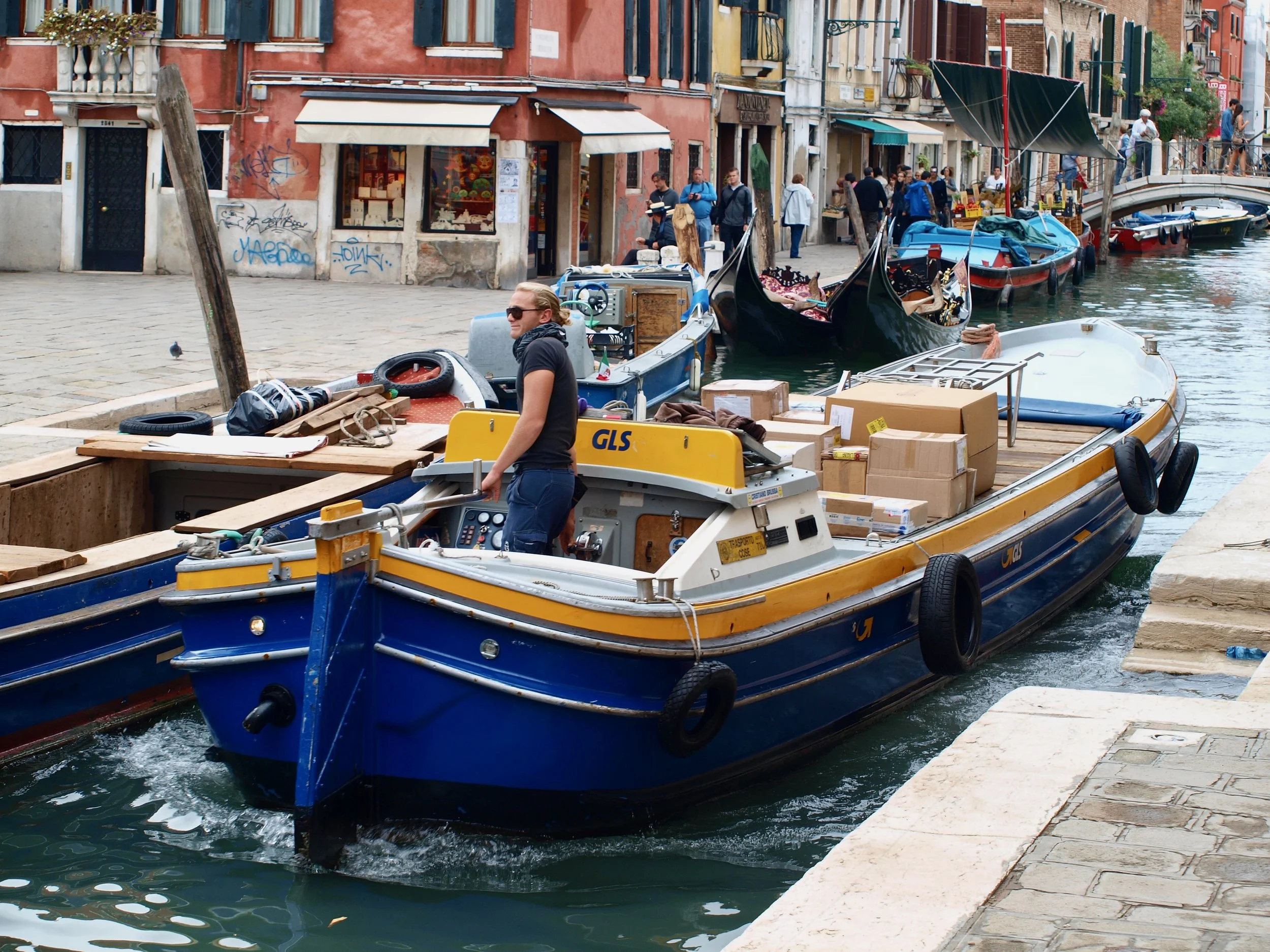 Voiliers amarrés le long d'une canal à Venise, avec des bâtiments colorés en arrière-plan.