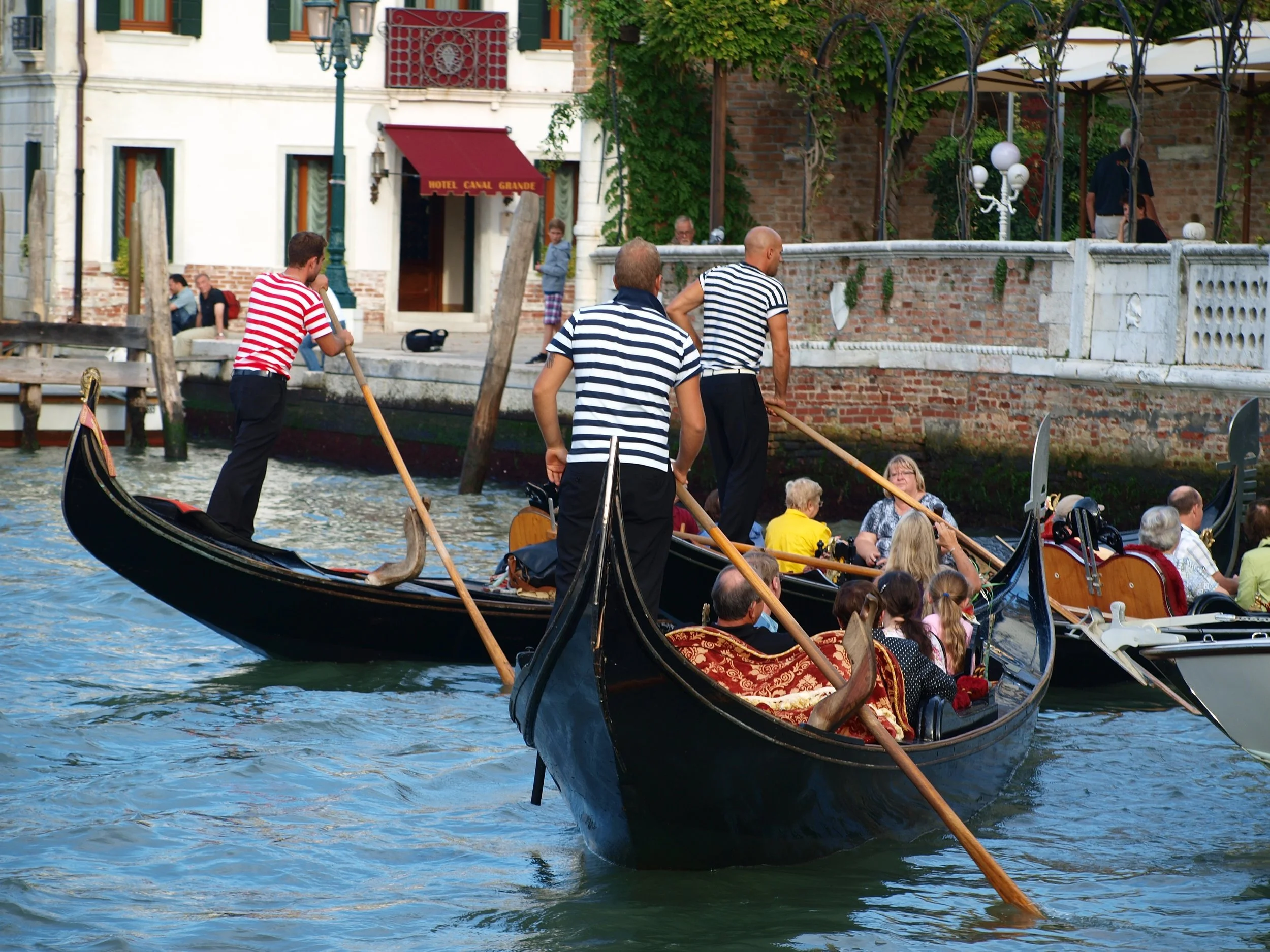 Des touristes en gondole à Venise, avec des bâtiments historiques en arrière-plan.