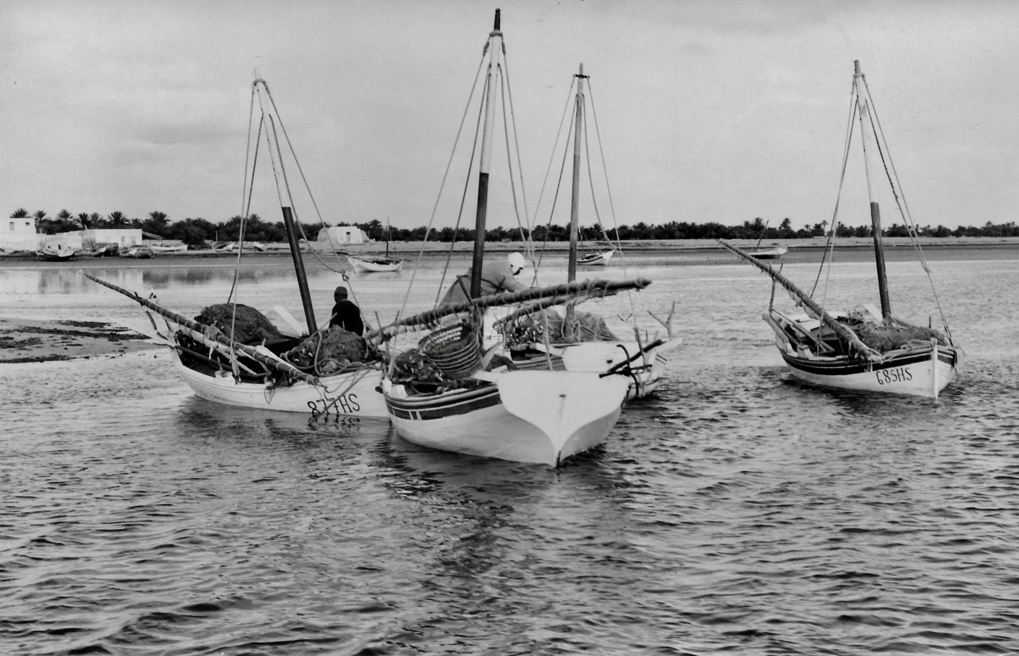 Deux bateaux de pêche en bois dans une rivière ou un lac, avec un pêcheur à bord d'un des bateaux.