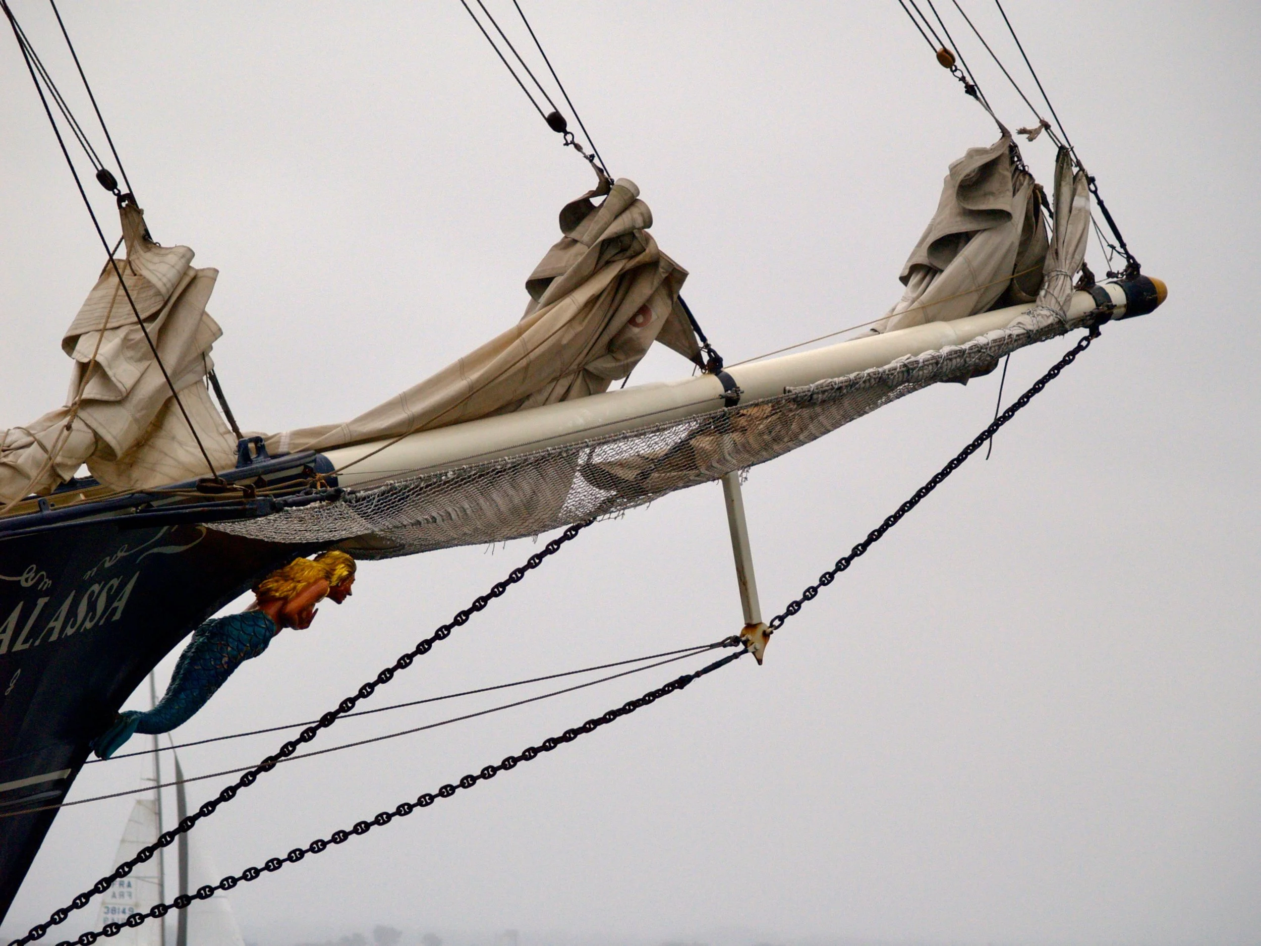 Les mâts, voiles et cordages d’un voilier avec un fond de ciel gris.