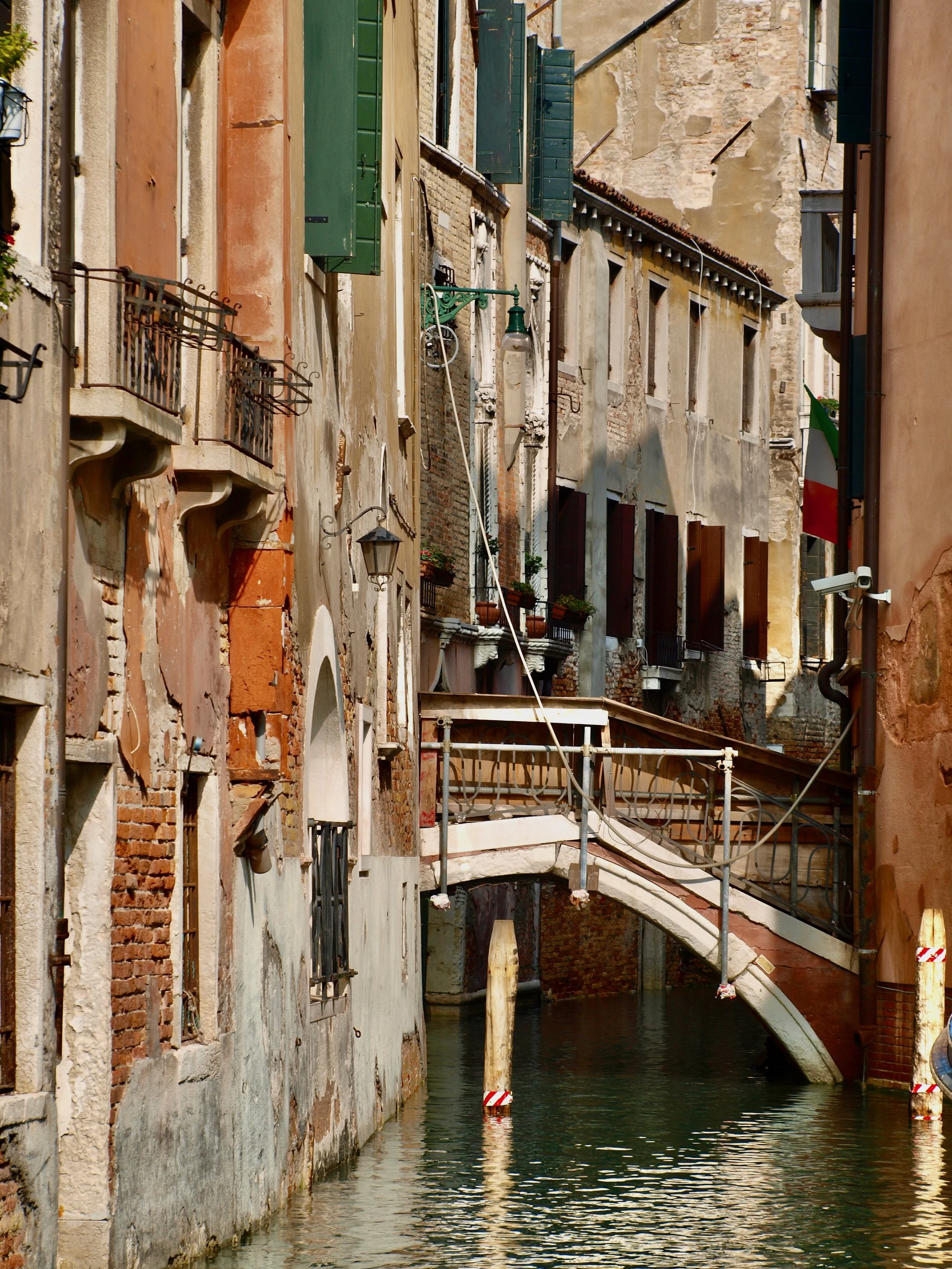 Les bâtiments colorés le long d'une canal à Venise, avec escaliers extérieurs, fenêtres avec volets et lampes anciennes.
