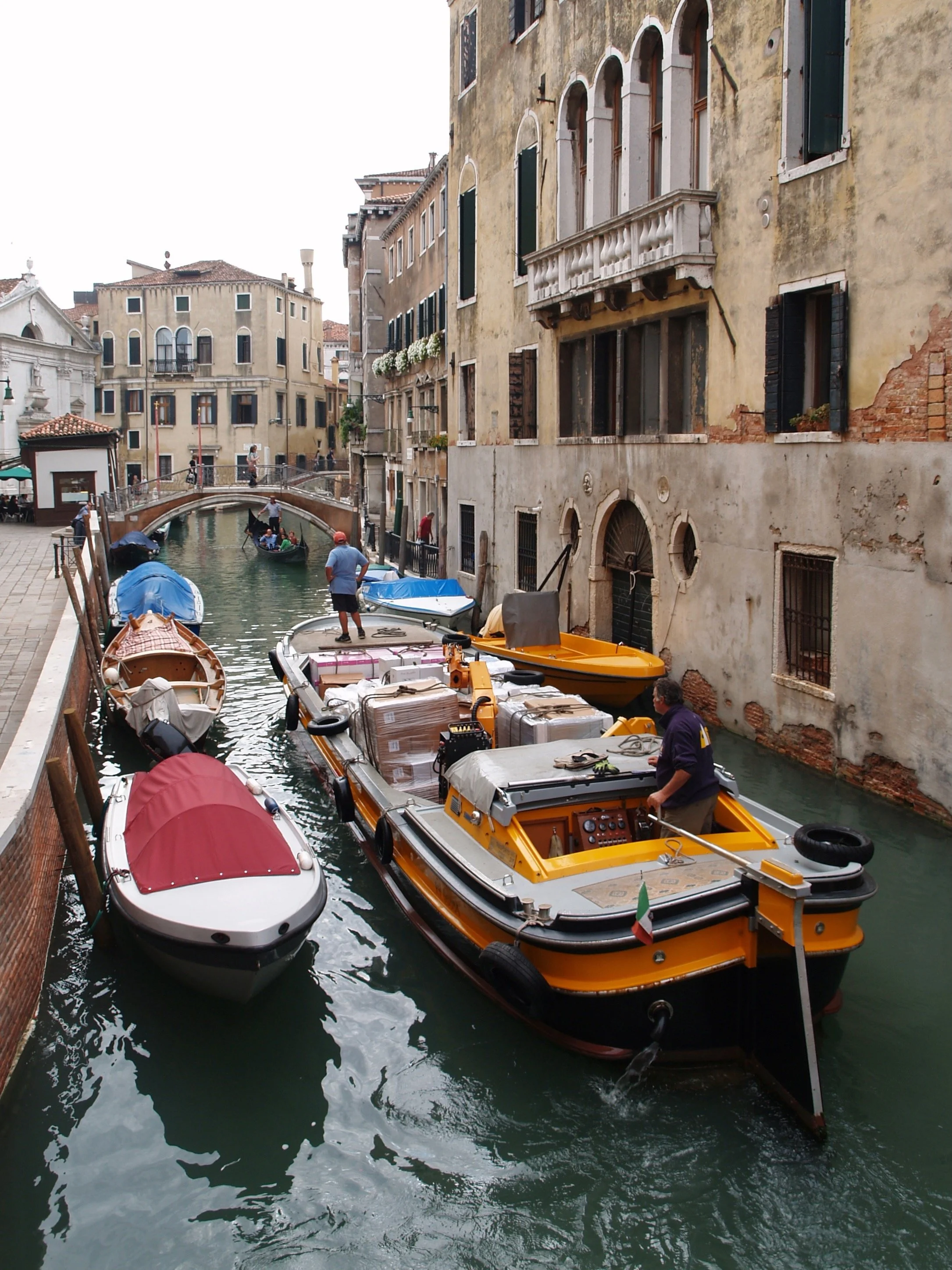 Bateaux amarrés le long d'un canal à Venise, en Italie, avec des bâtiments anciens en pierre et des fenêtres à volets verts.