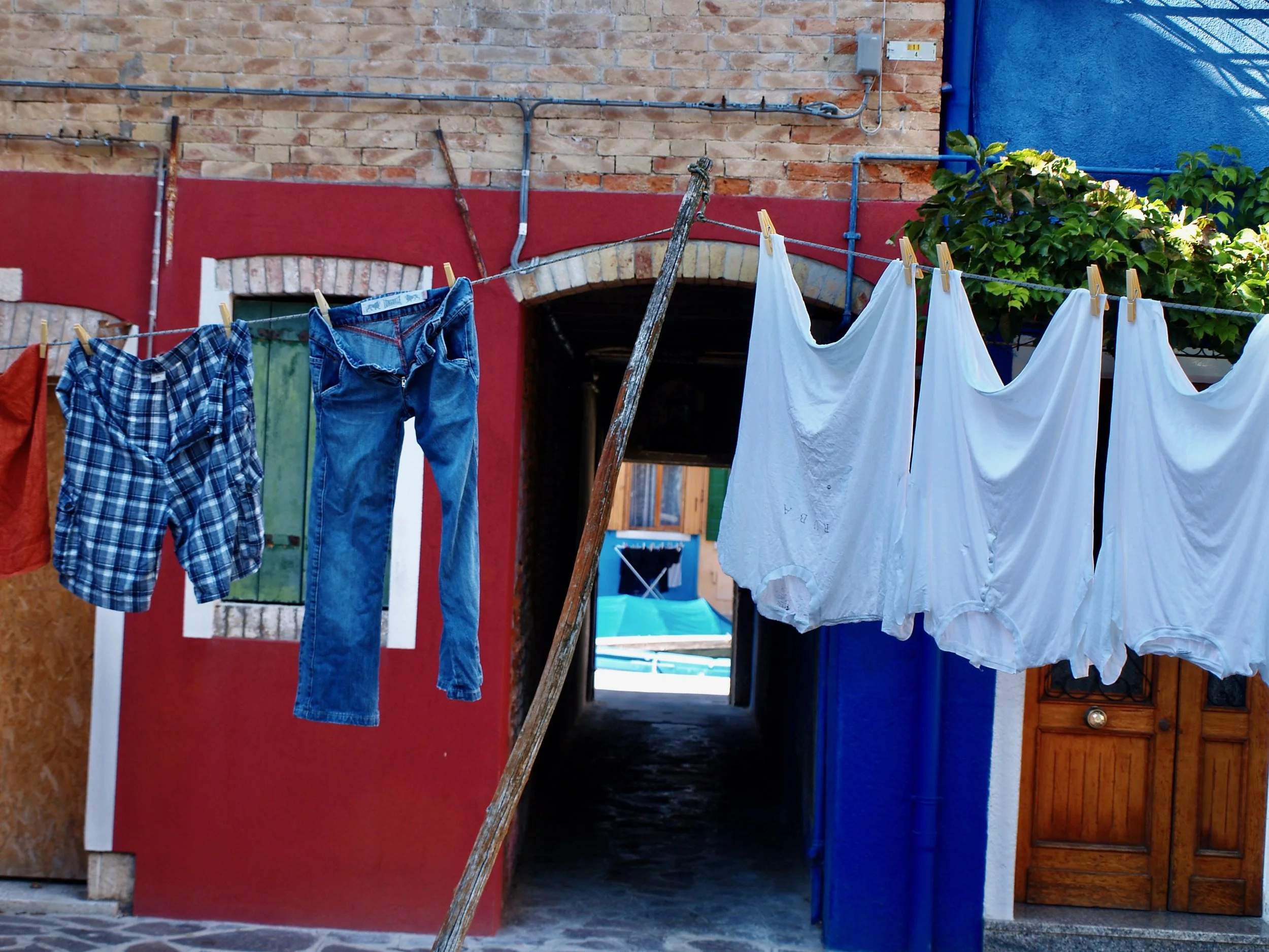 Linge à laver suspendu à une corde à linge en extérieur, avec un mur en briques en arrière-plan.