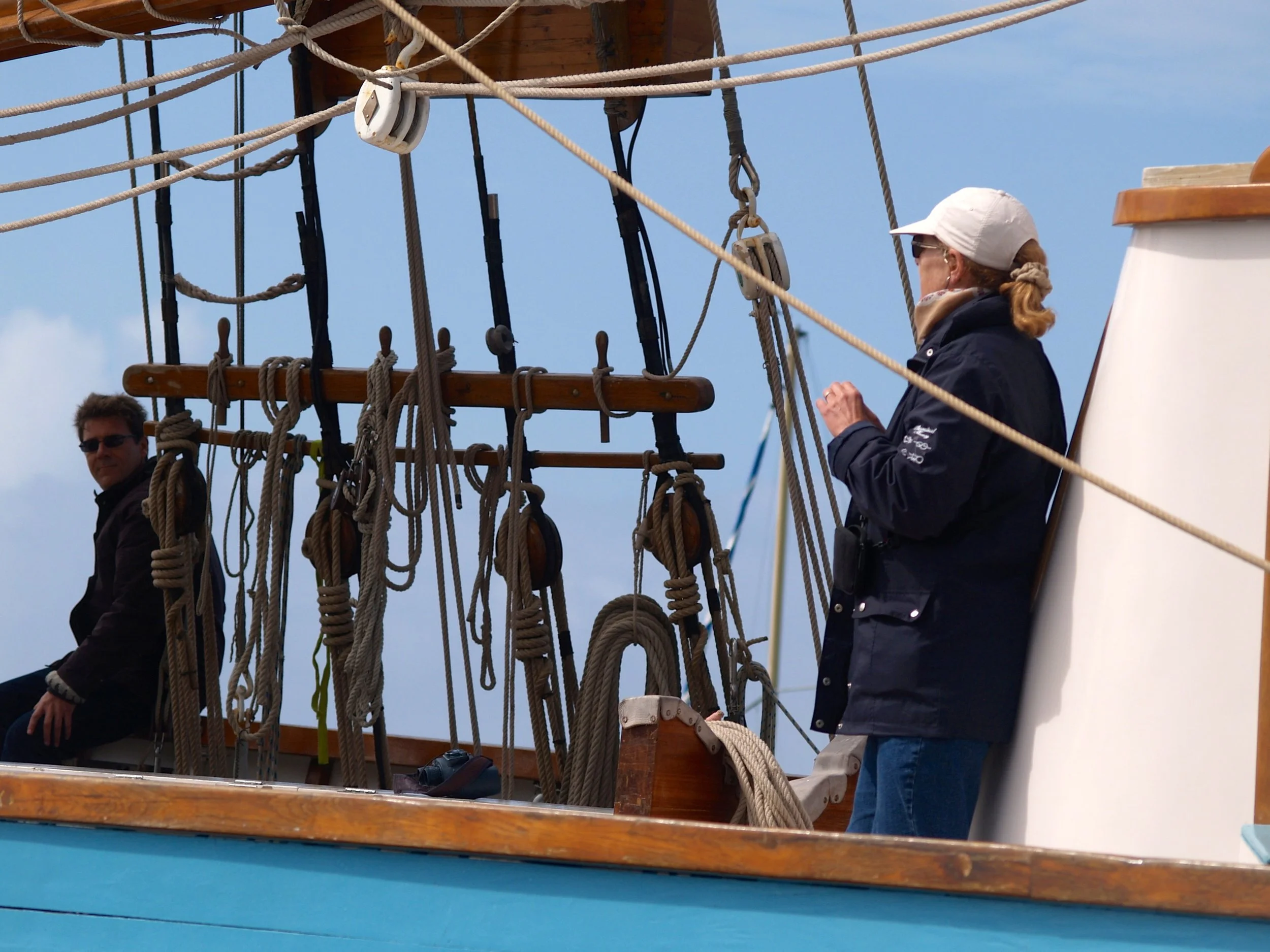 Personne sur un navire en train de faire des gestes près de la corde et des instruments de navigation. Fond de ciel bleu avec quelques nuages.