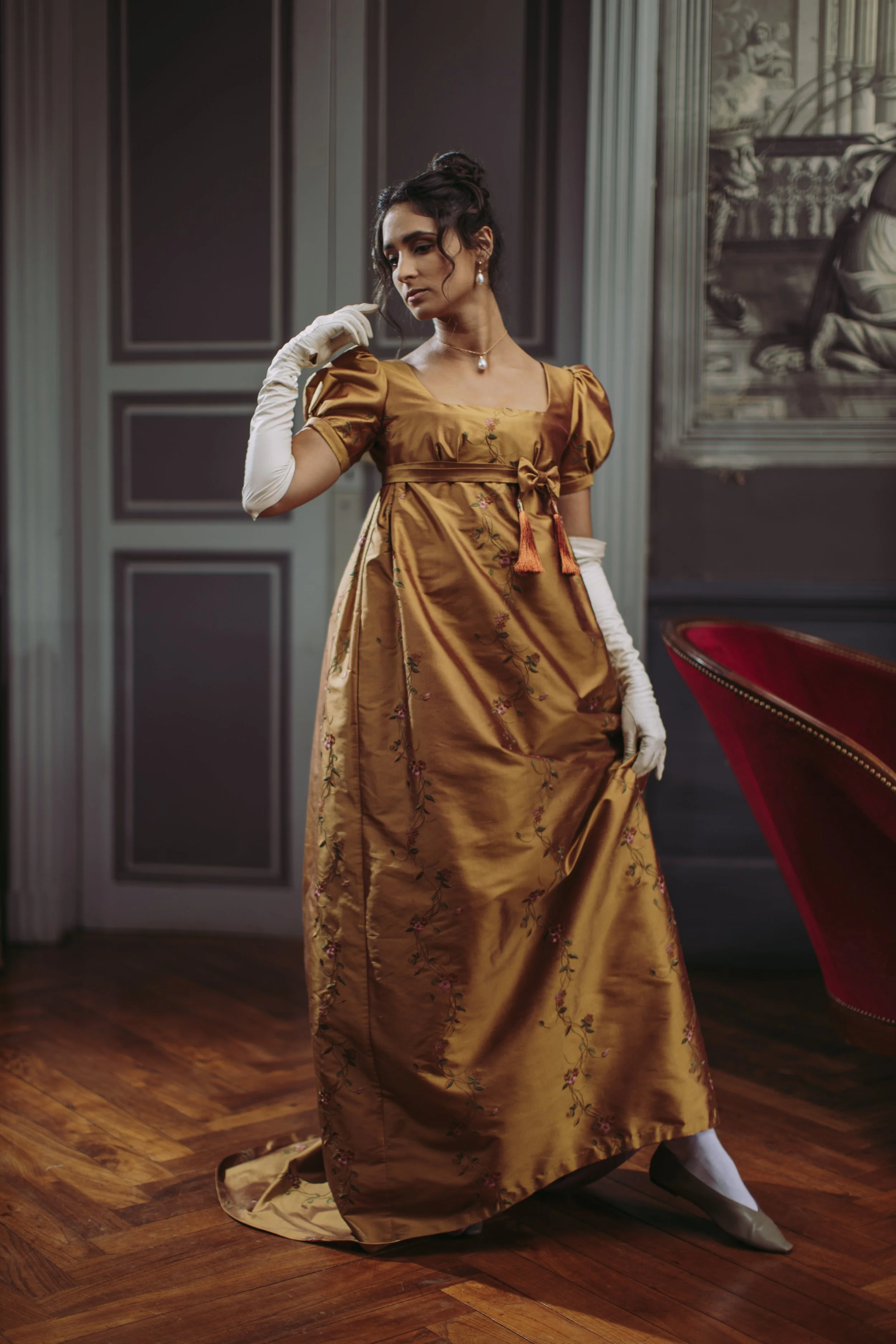 Une femme habillée en robe premier empire historique dans un château avec détails couture