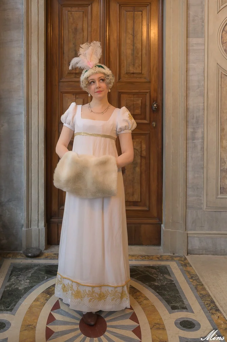 Une femme habillée d'une robe premier empire historique blanc avec des broderies couture dorés, 19ème siècle