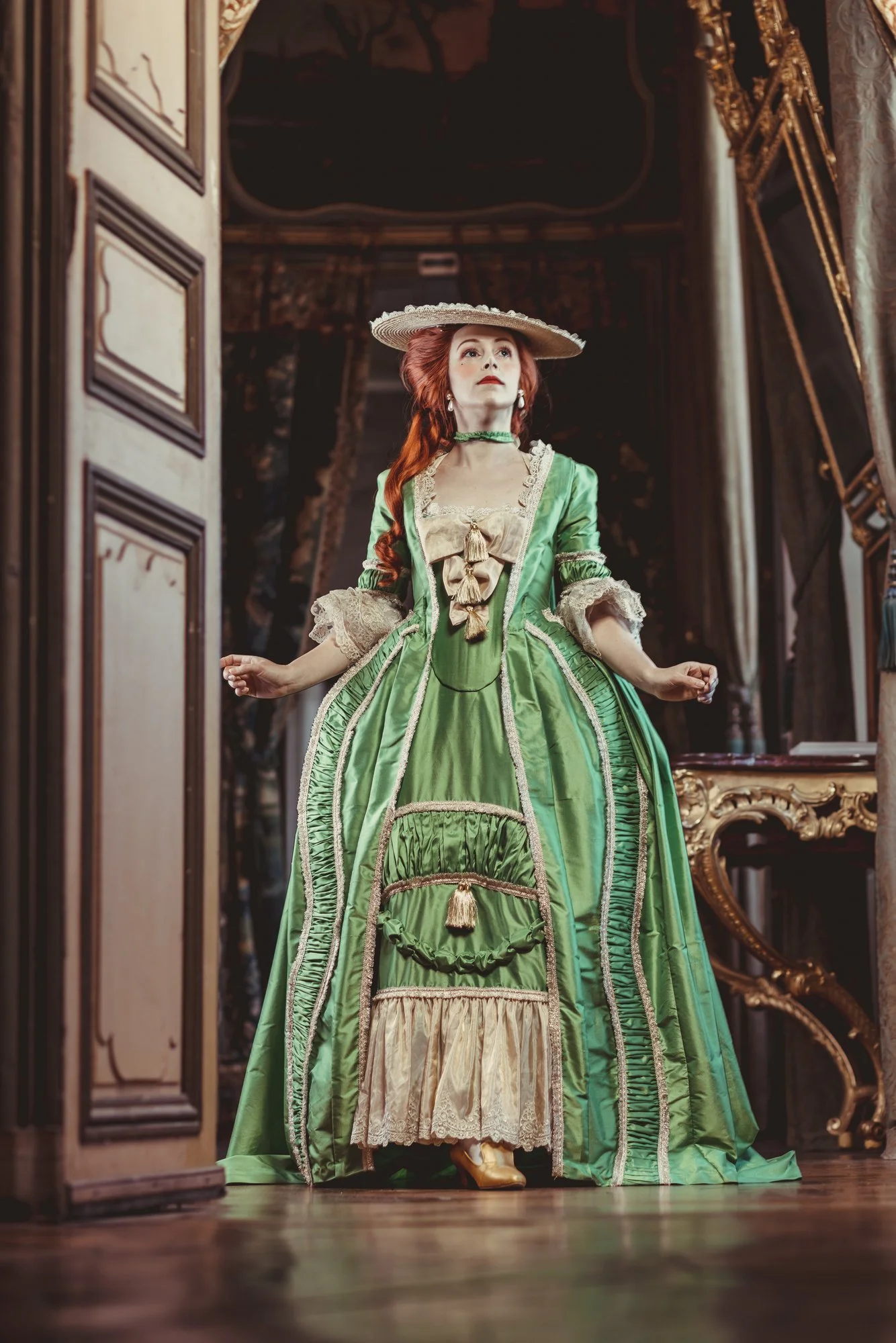 Une femme en costume historique en soie verte robe à la française 18ème siècle détails couture dans un château rococo