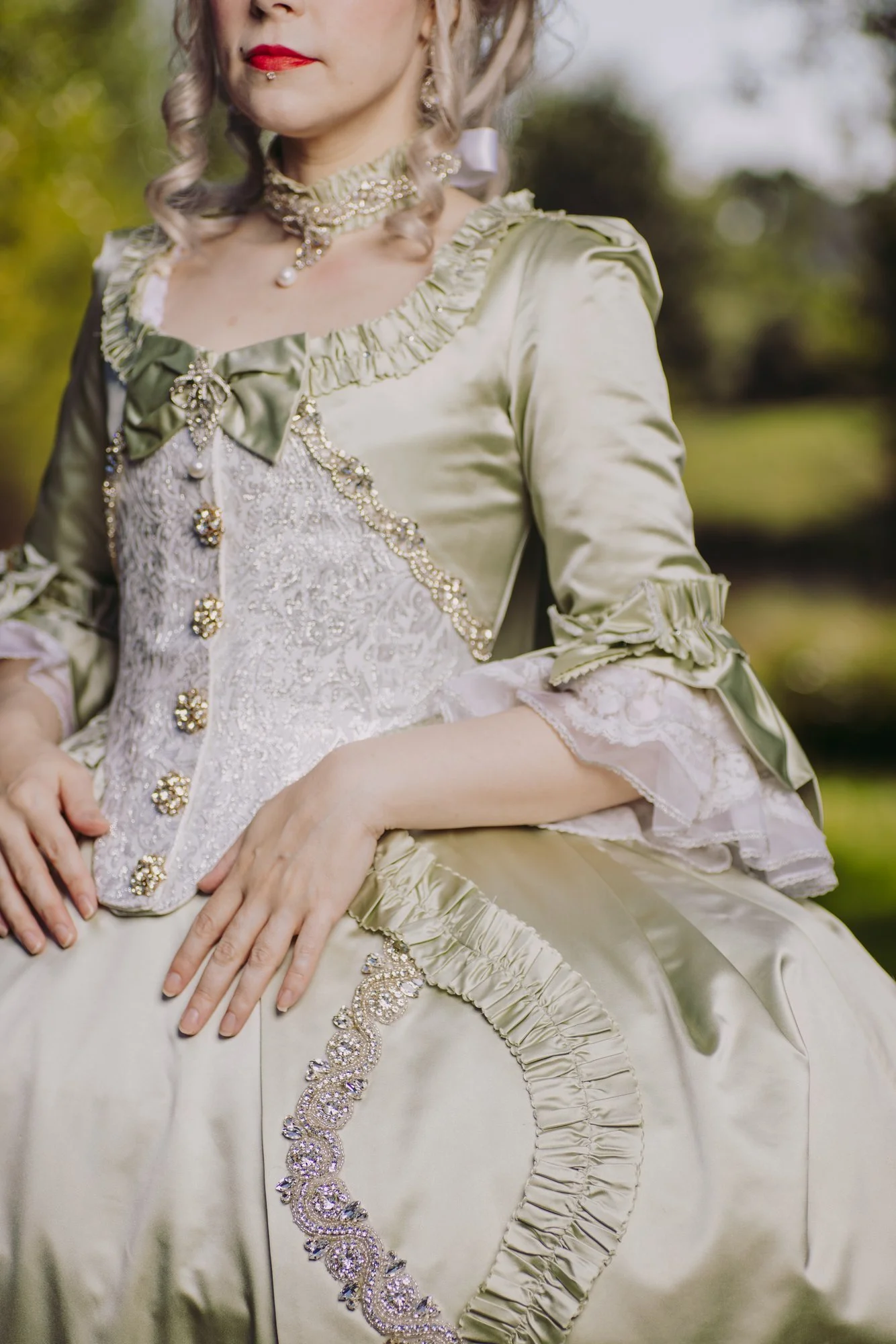 Une femme en robe à la française historique 18ème siècle rococo détails couture élaboré avec des détails en perles et broderies, portant des bijoux  