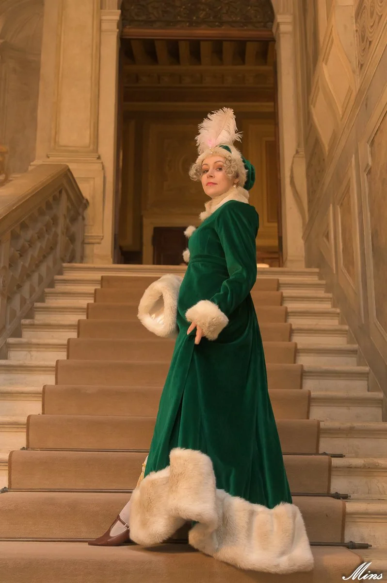 Une femme habillée d'une veste verte en velours premier empire avec des détails en fourrure blanche, 19ème siècle costume historique