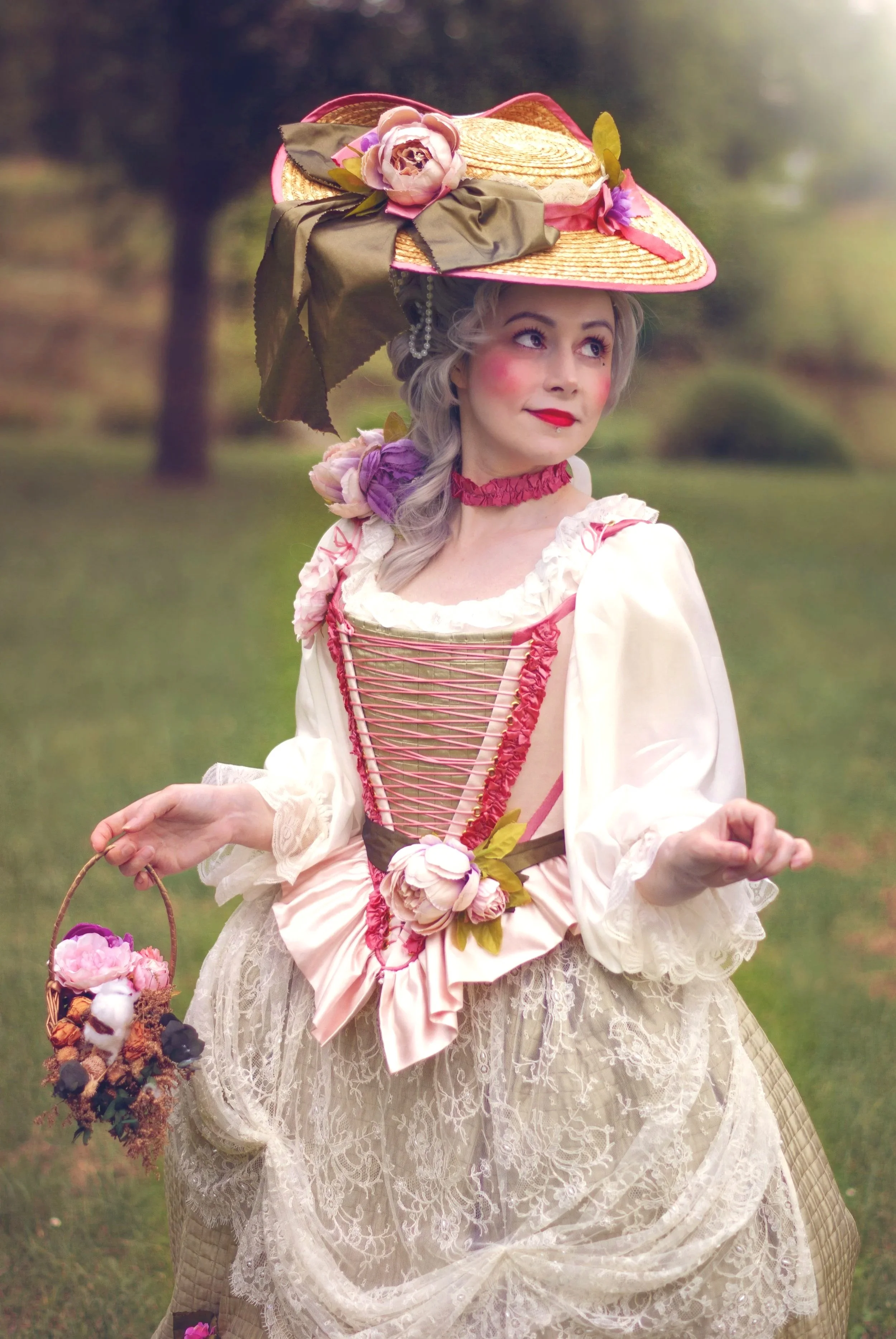Une femme portant un chapeau en paille orné de fleurs et de rubans, vêtue d'une robe vintage en dentelle avec des détails en rose. style rococo bergère marie antoinette Elle tient un panier de fleurs et se tient dans un décor naturel verdoyant.