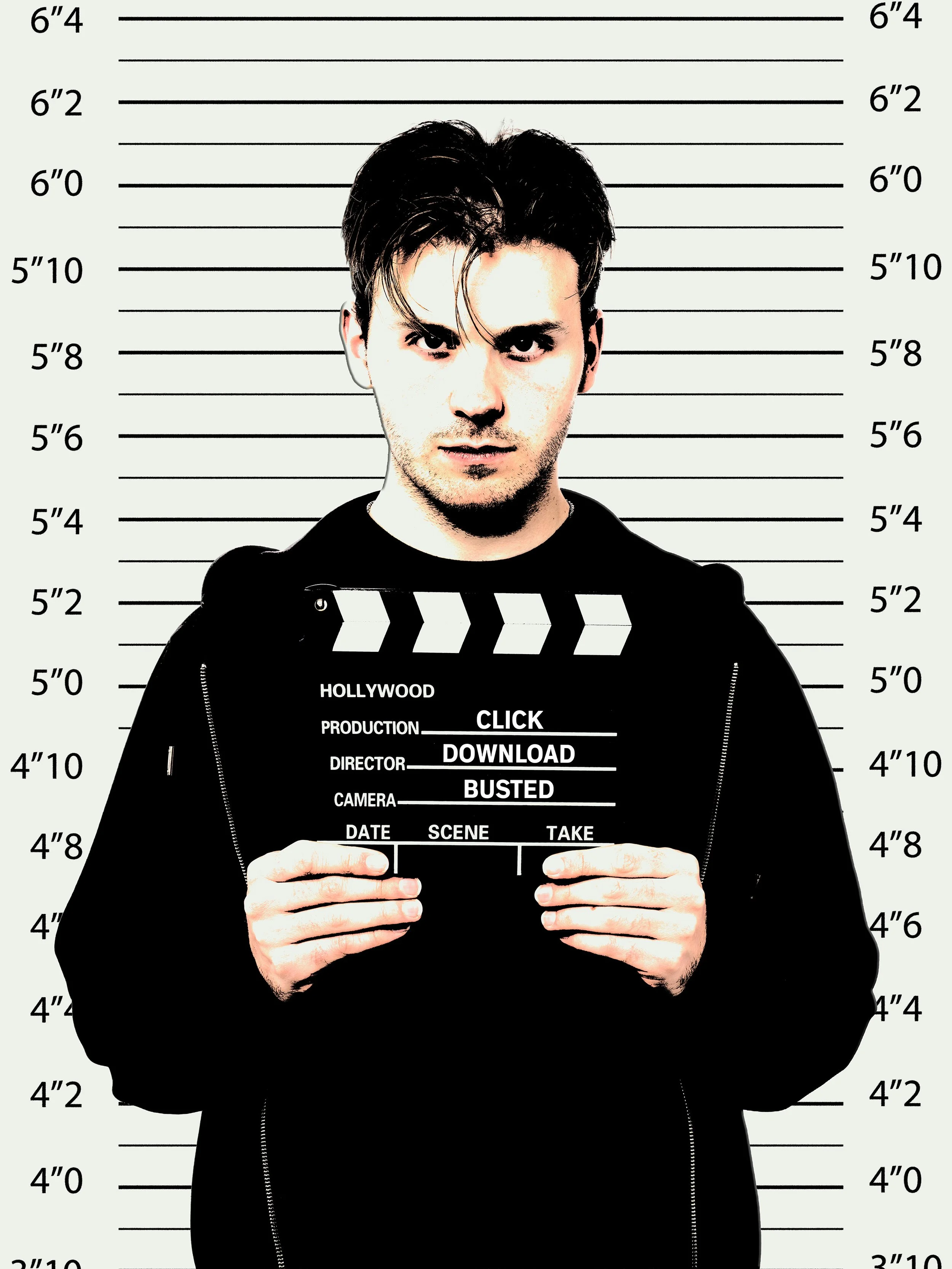 A man with dark hair and light skin standing in front of a height measurement backdrop, holding a clapperboard with the words HOLLYWOOD, PRODUCTION, DIRECTOR, CAMERA, DATE, SCENE, TAKE, CLICK, DOWNLOAD, BUSTED printed on it.