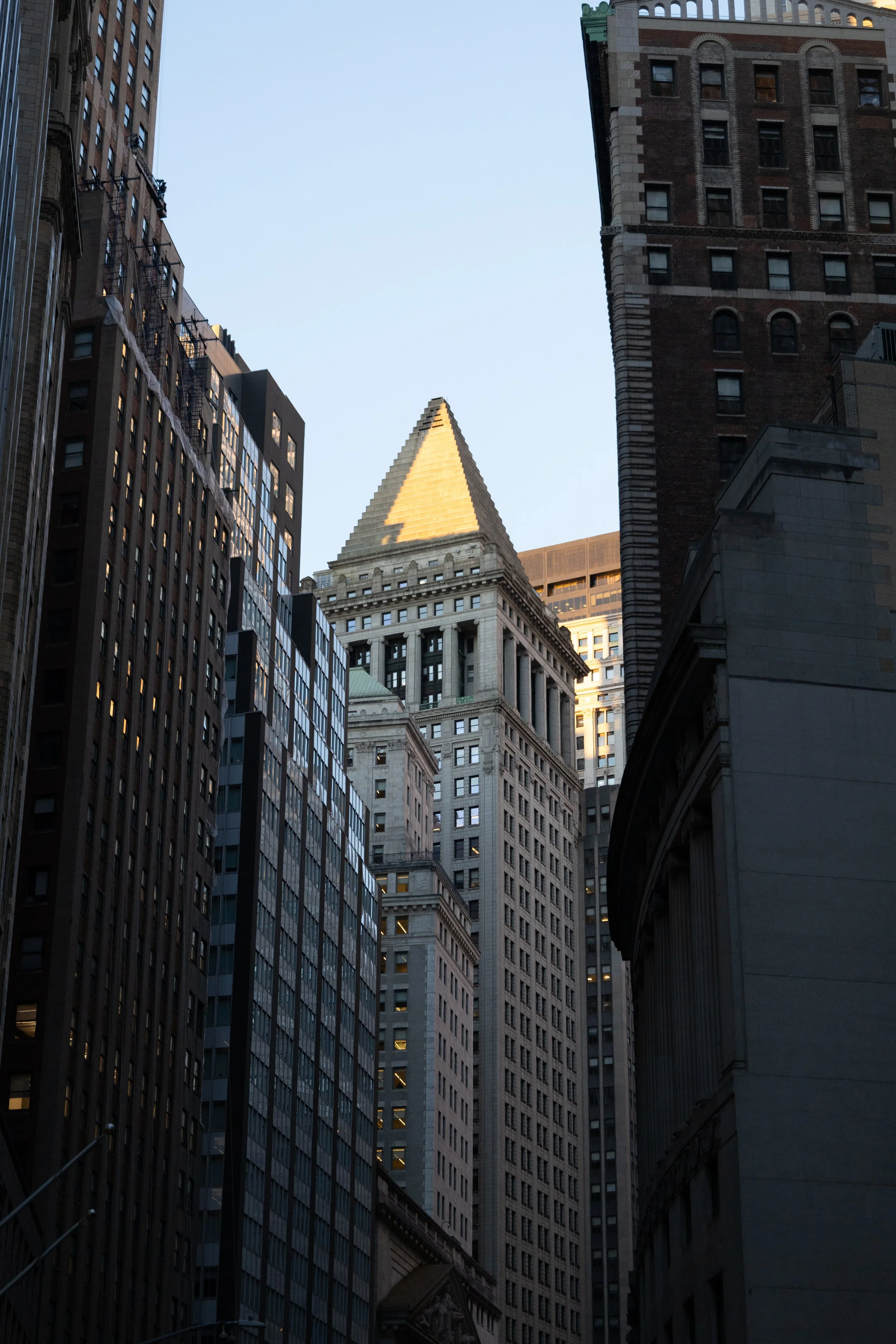 A cityscape with tall buildings, including one with a golden pyramid-shaped top, captured during early evening or late afternoon.
