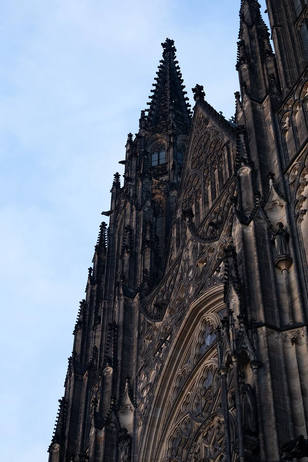 Close-up view of a Gothic cathedral's ornate facade and spires against a blue sky.