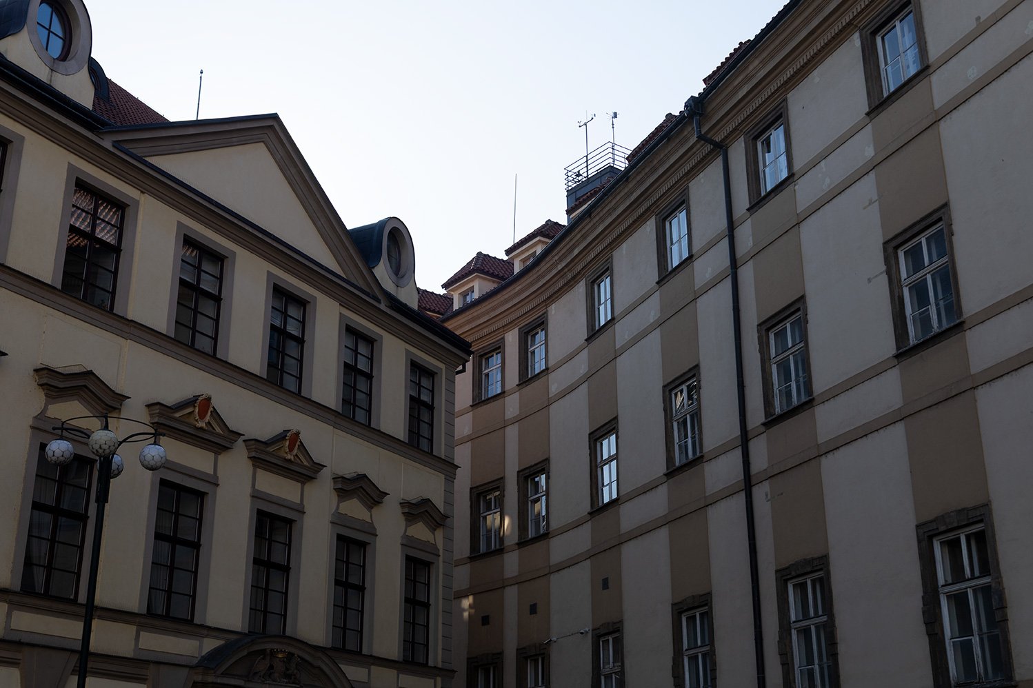 Photo of European-style older buildings with multiple windows, a streetlamp with six globe lights, and a clear sky.