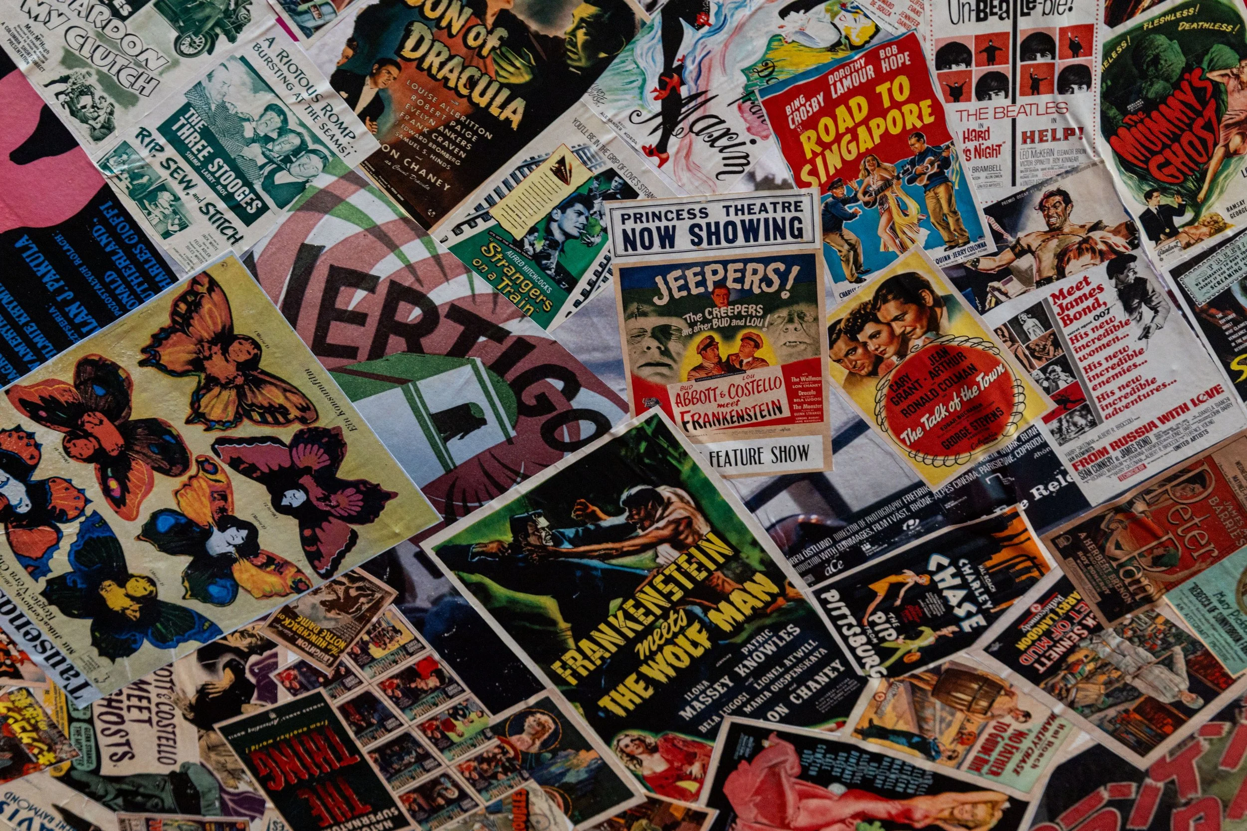 Collage of vintage theater and movie posters, advertisements, and playbills scattered across a surface.
