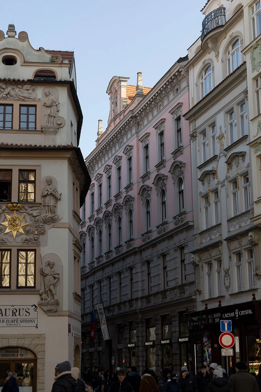Street scene with ornate historic buildings and people walking, in a European city.