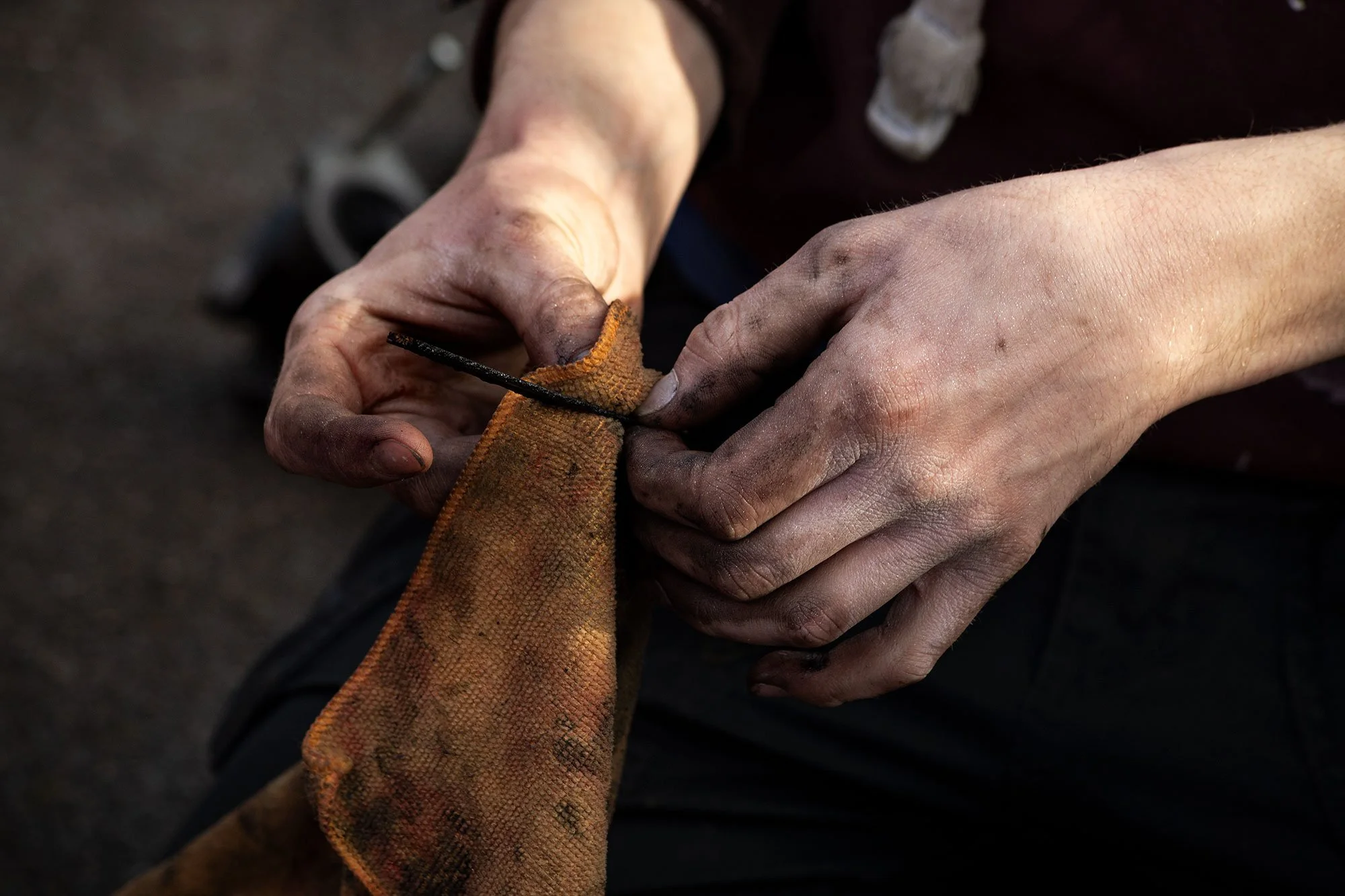 Close-up of a blacksmith's hands working with a horseshoe, holding a tool and a horseshoe on an anvil.
