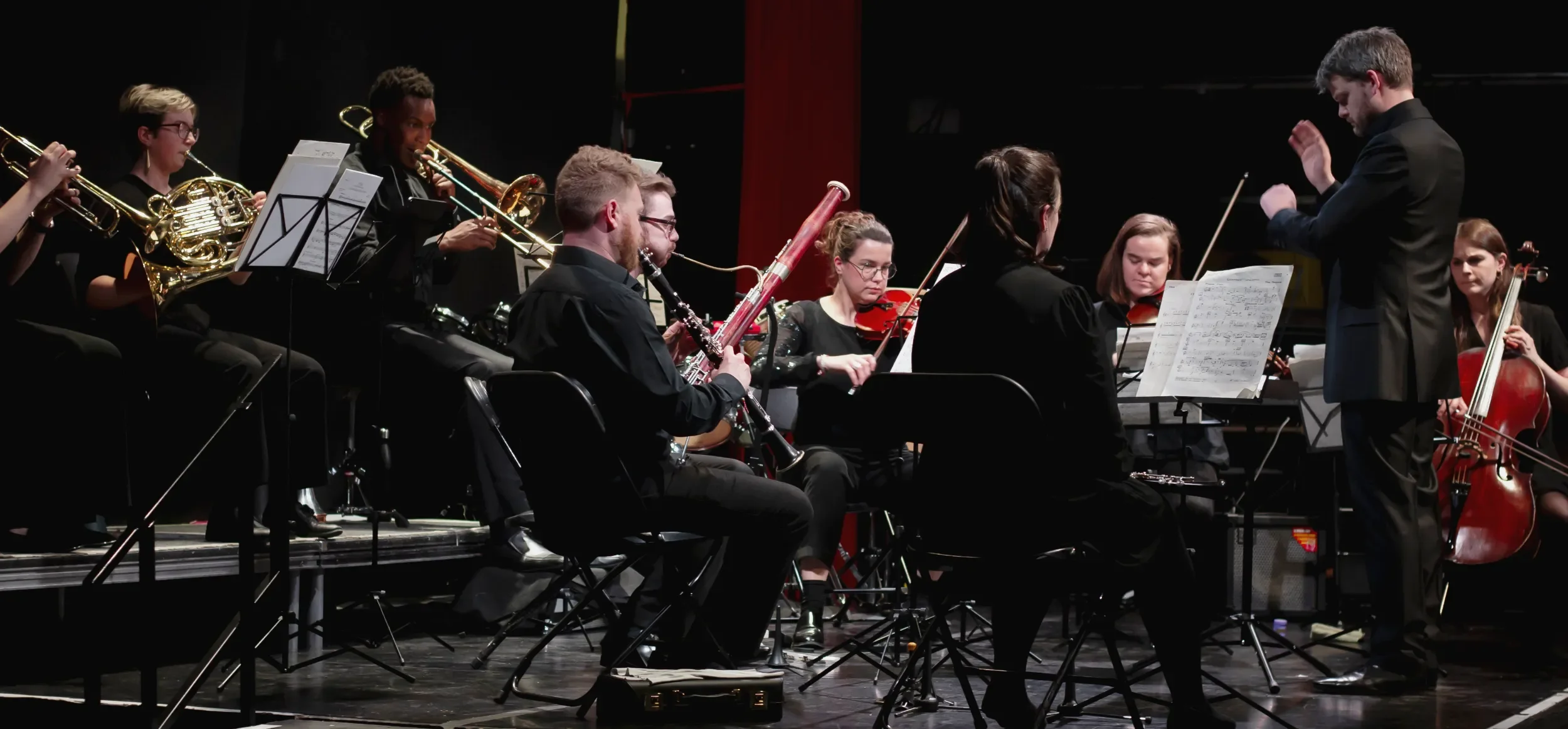 Matthew Hardy conducting players from East London Music Group on stage at Rich Mix in Shoreditch, London, UK