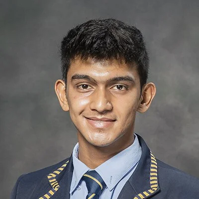 Young man in school uniform with a blazer and tie, smiling at the camera