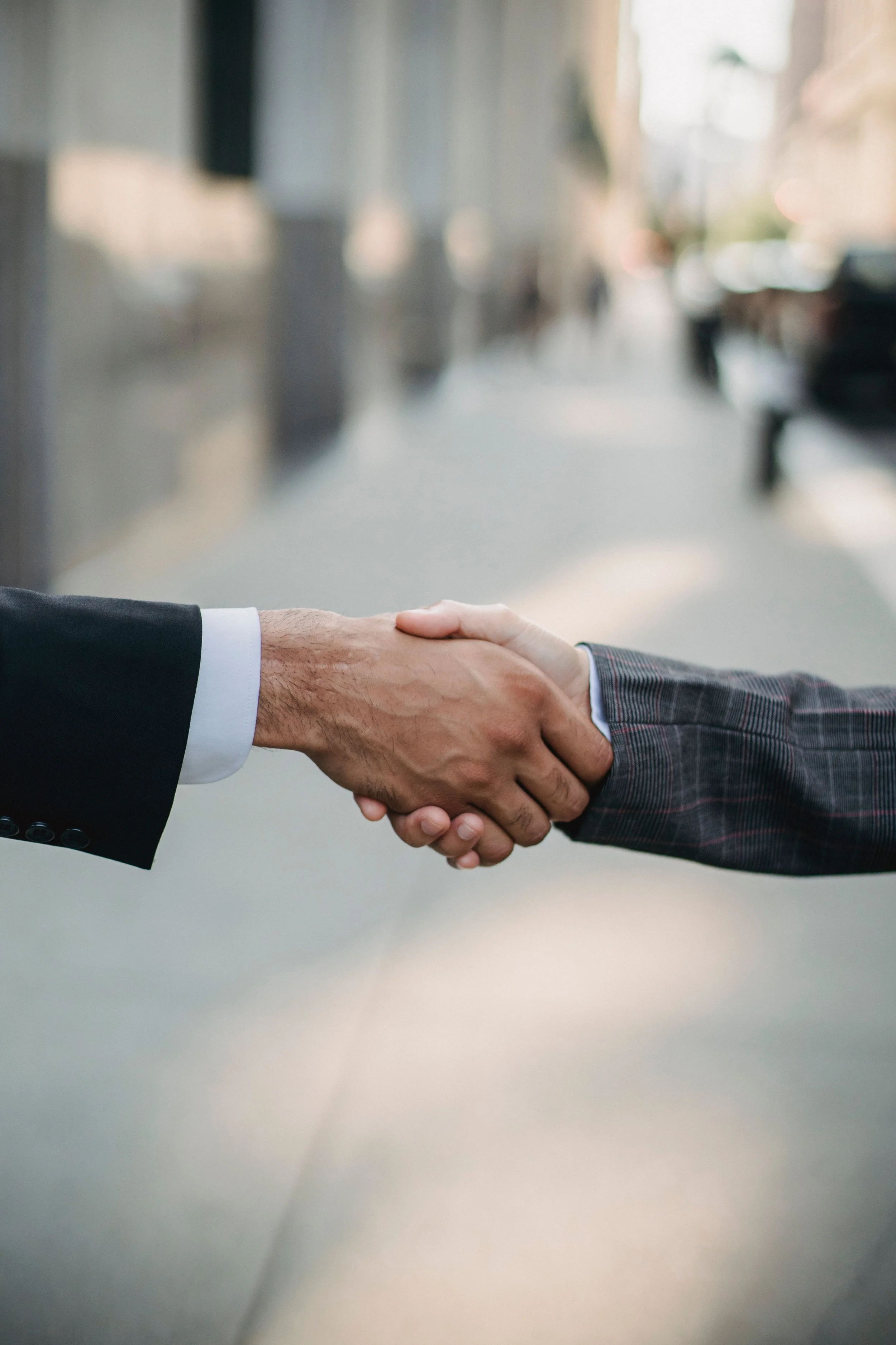 Close-up of two people in business suits shaking hands.