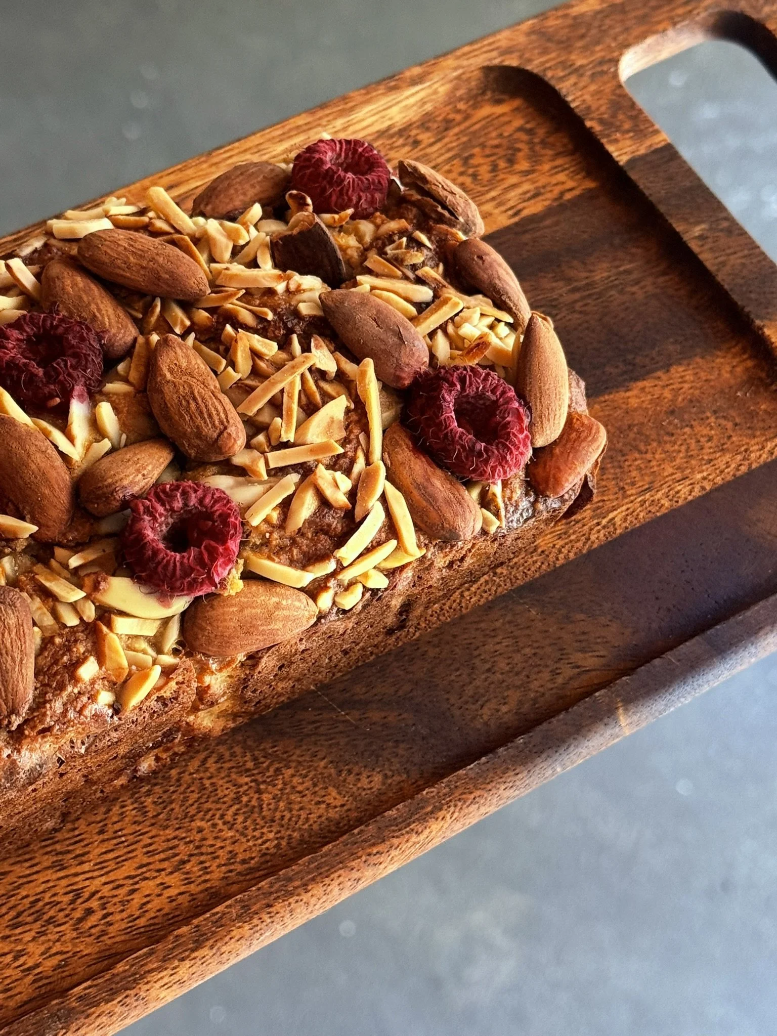 Close-up of a wooden serving board with assorted nuts and dried berries.