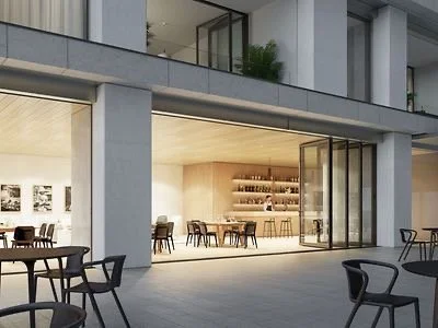 Modern building with indoor and outdoor seating, open glass doors, and a woman inside at a countertop